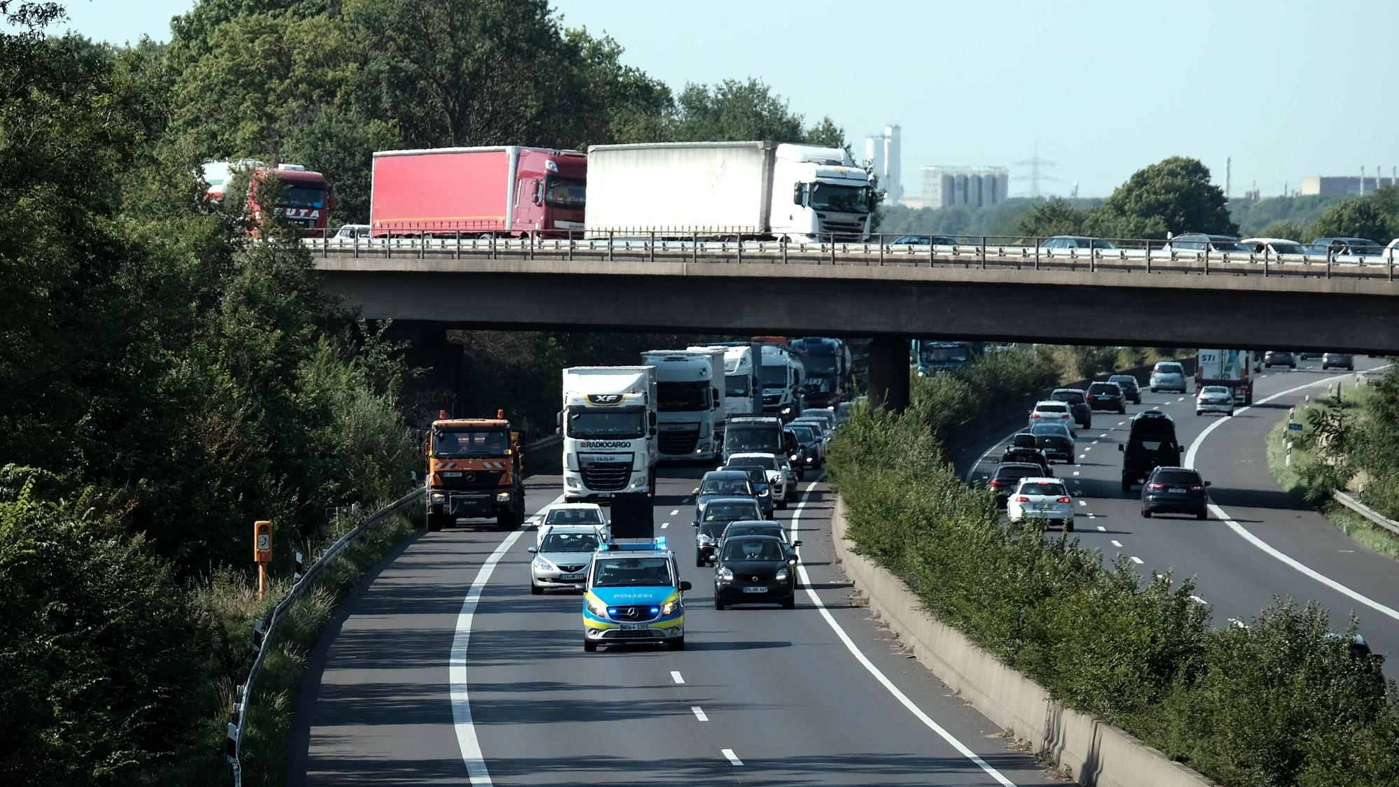 Ein Polizeiauto fährt über die A57. Dahinter fahren weitere Autos.