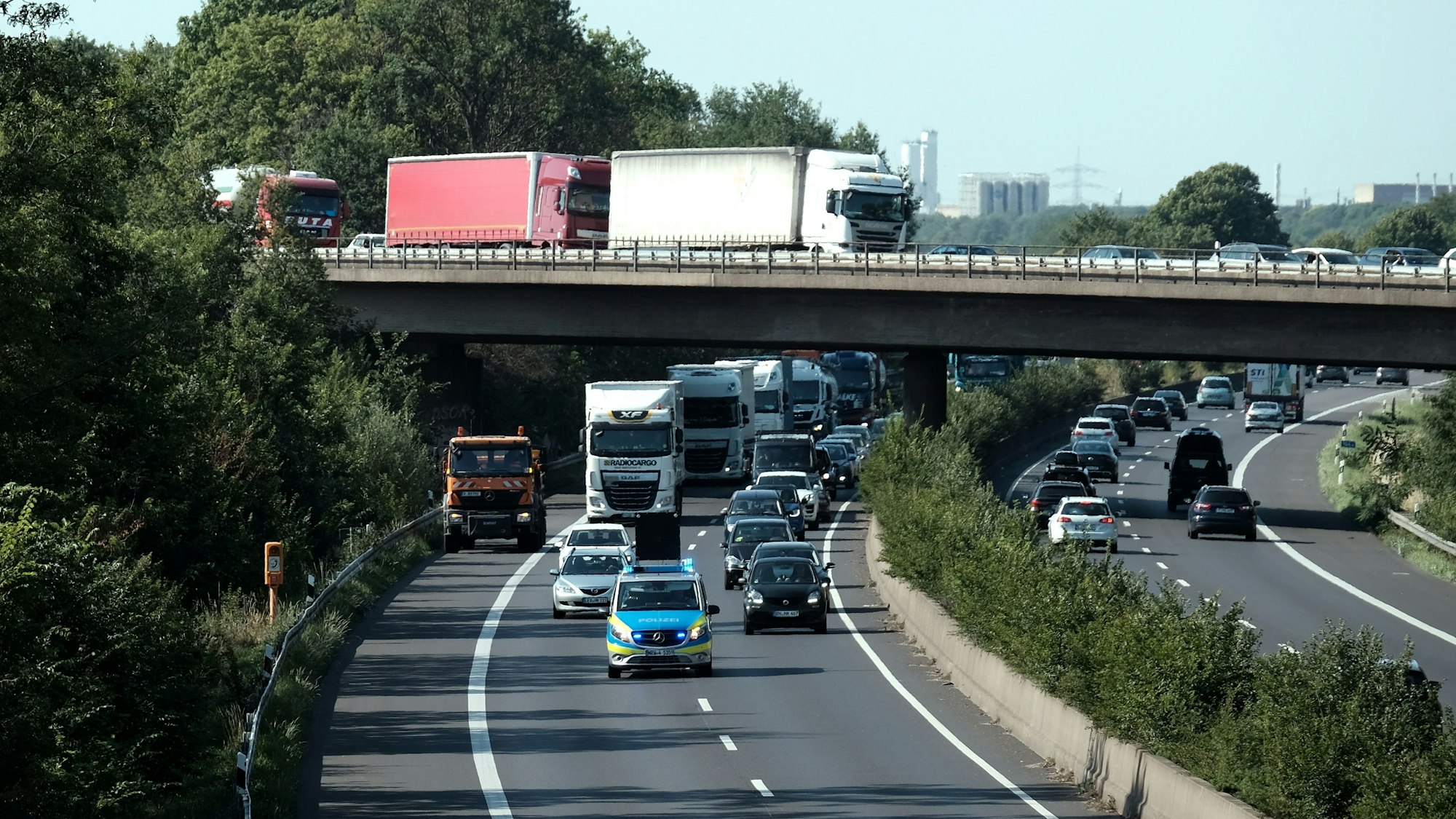 Ein Polizeiauto fährt über die A57. Dahinter fahren weitere Autos.