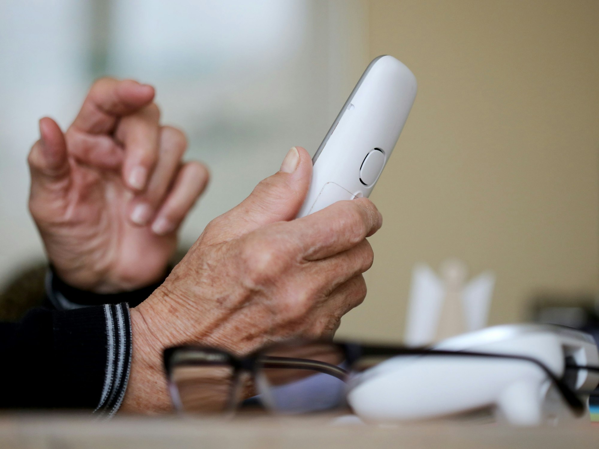 Eine ältere Dame nimmt in ihrer Wohnung ein Telefongespräch an.