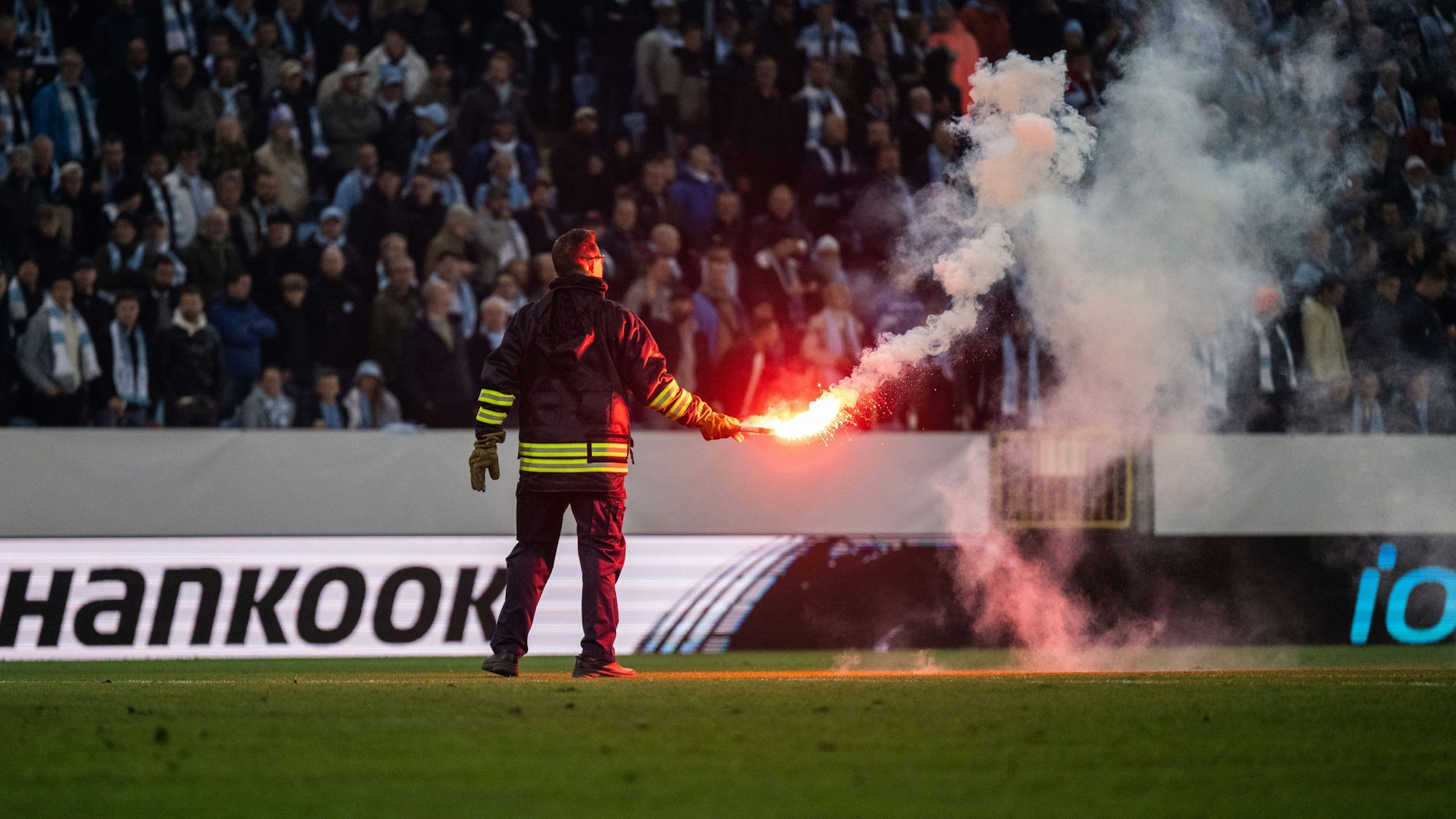Ein Feuerwehrmann bringt eine brennende Fackel nach der Unterbrechung des Spiels zwischen Malmö FF und Union Berlin vom Feld.