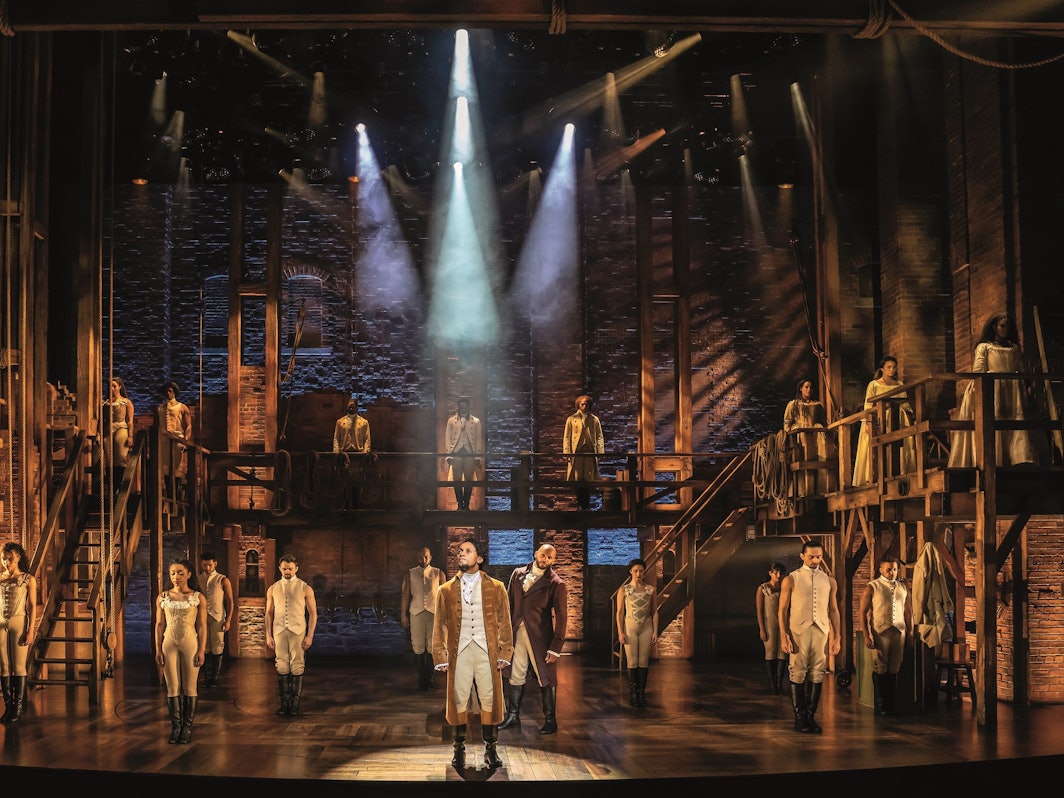 Die Kulisse und einige der Darsteller und Darstellerinnen des Musicals „Hamilton“, welches ab dem 6. Oktober in Hamburg besucht werden kann.