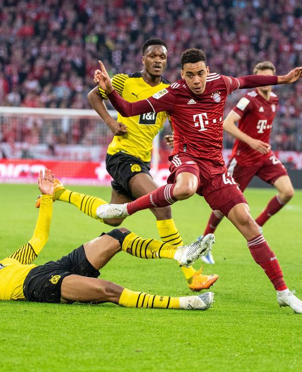 Dan-Axel Zagadou von Borussia Dortmund (M), Jamal Musiala vom FC Bayern München (r.) und Jude Bellingham von Borussia Dortmund (unten) im Kampf um den Ball im Duell Bayern gegen den BVB.