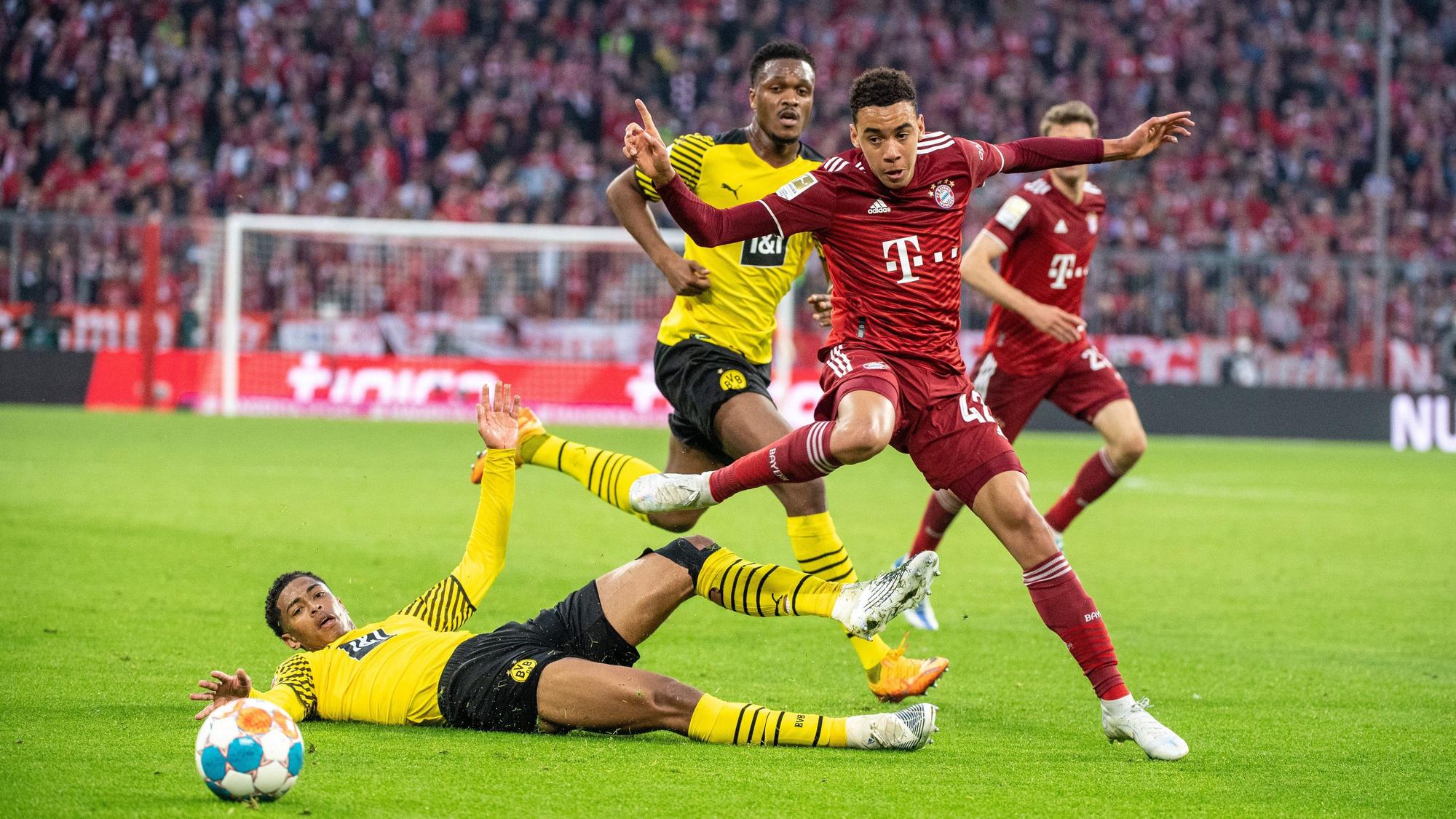 Dan-Axel Zagadou von Borussia Dortmund (M), Jamal Musiala vom FC Bayern München (r.) und Jude Bellingham von Borussia Dortmund (unten) im Kampf um den Ball im Duell Bayern gegen den BVB.