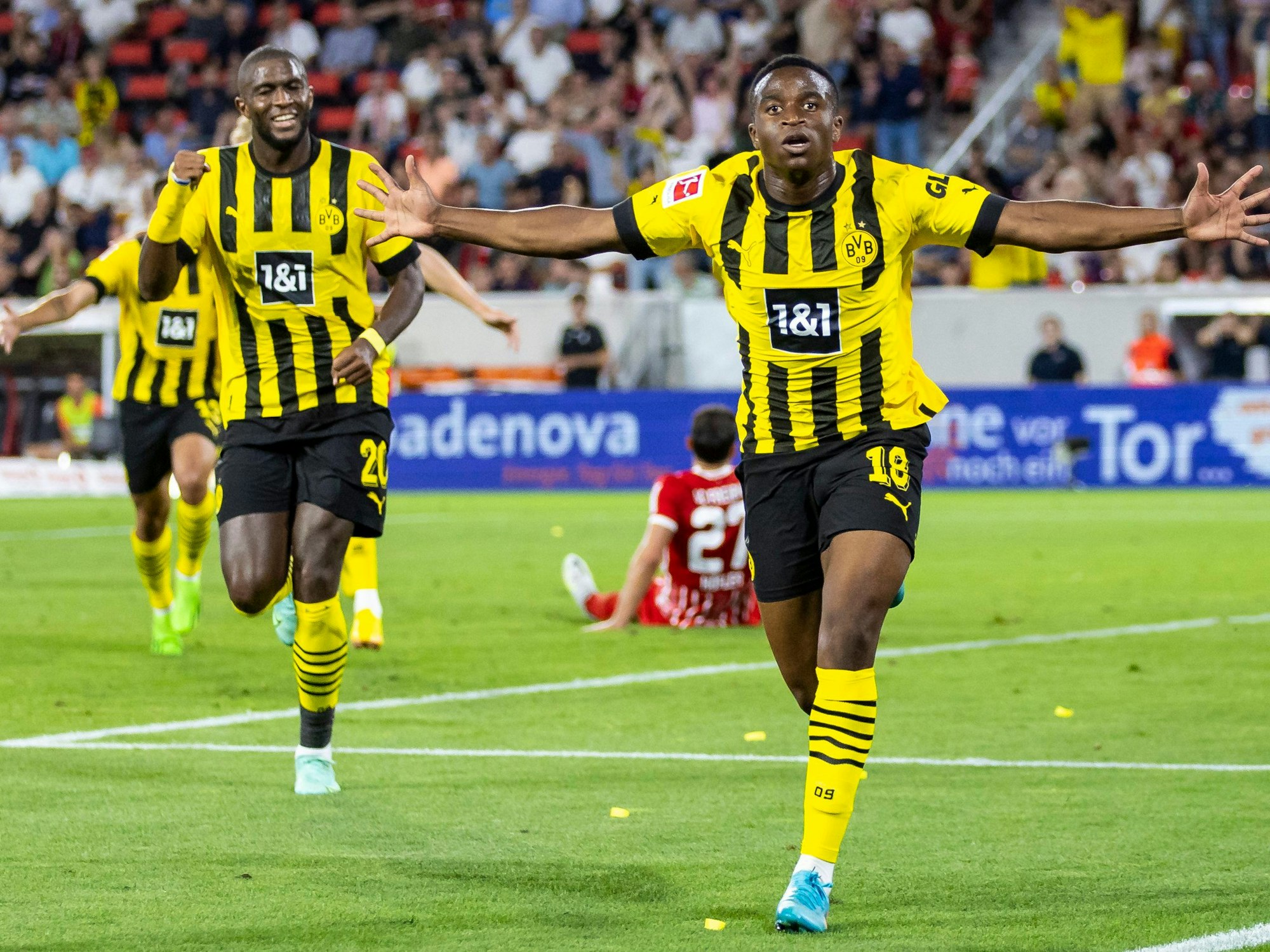 Youssoufa Moukoko (r.) jubelt mit weit ausgestreckten Armen nach seinem Tor.