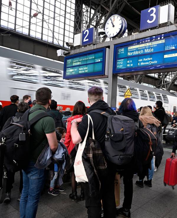 Reisende stehen am Hauptbahnhof und warten auf ihre Weiterfahrt.