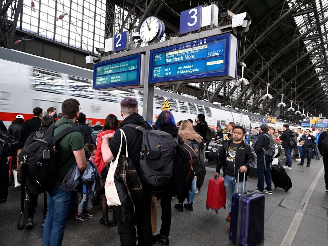 Reisende stehen am Hauptbahnhof und warten auf ihre Weiterfahrt.