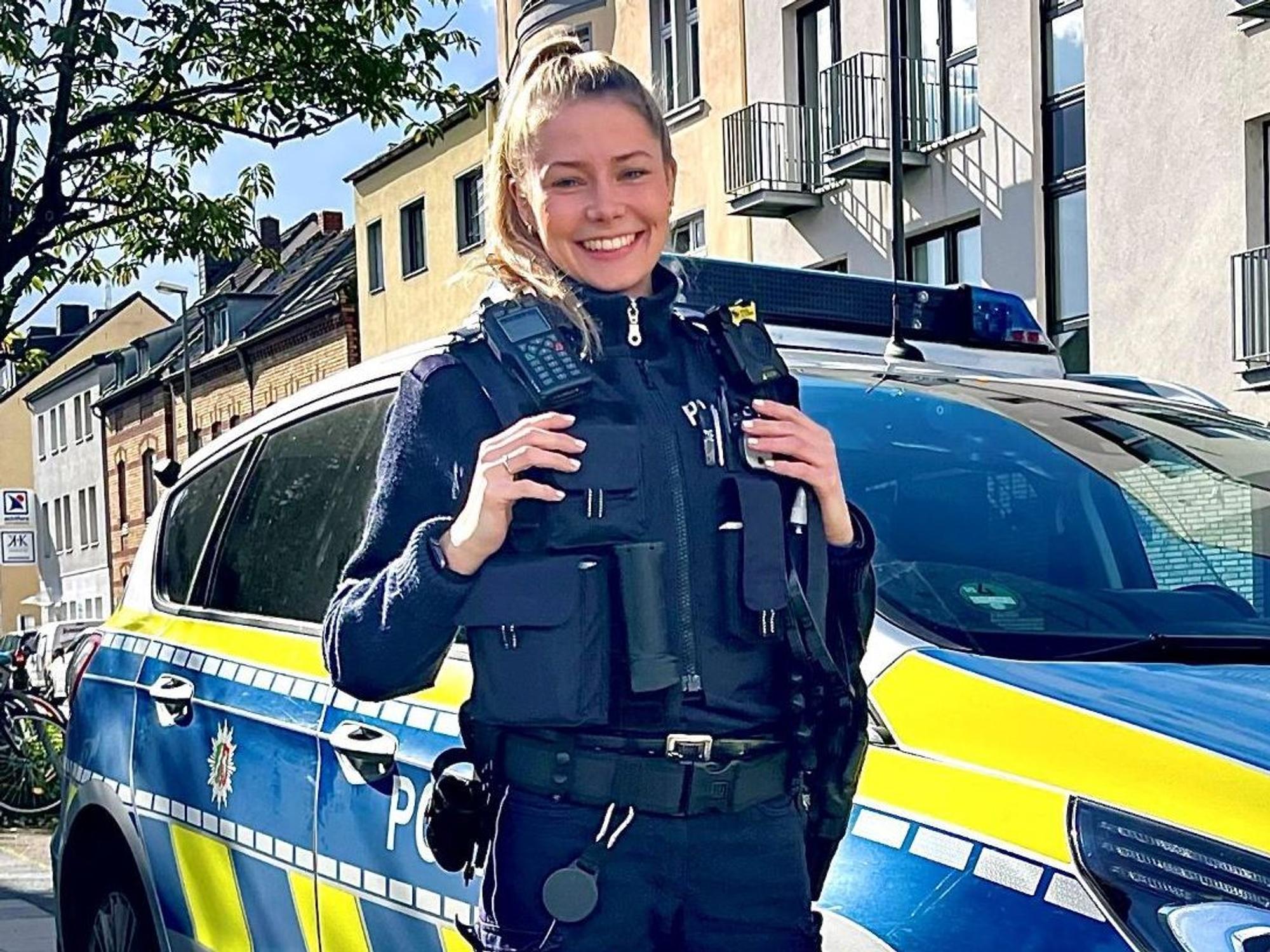 Polizeikommissarin Mira Asbach (29) von der Kölner Polizei steht vor einem Streifenwagen.