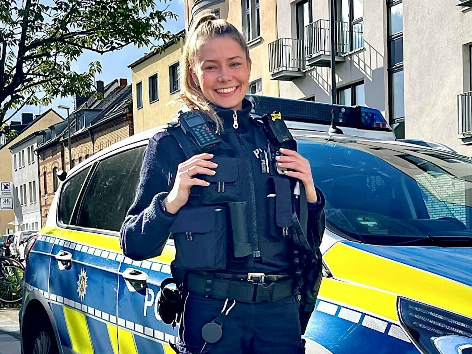 Polizeikommissarin Mira Asbach (29) von der Kölner Polizei steht vor einem Streifenwagen.
