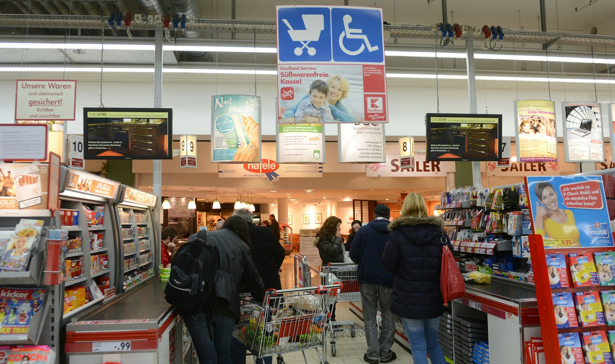 Kundinnen und Kunden stehen im Kassenbereich einer Kaufland-Filiale in der Schlange.