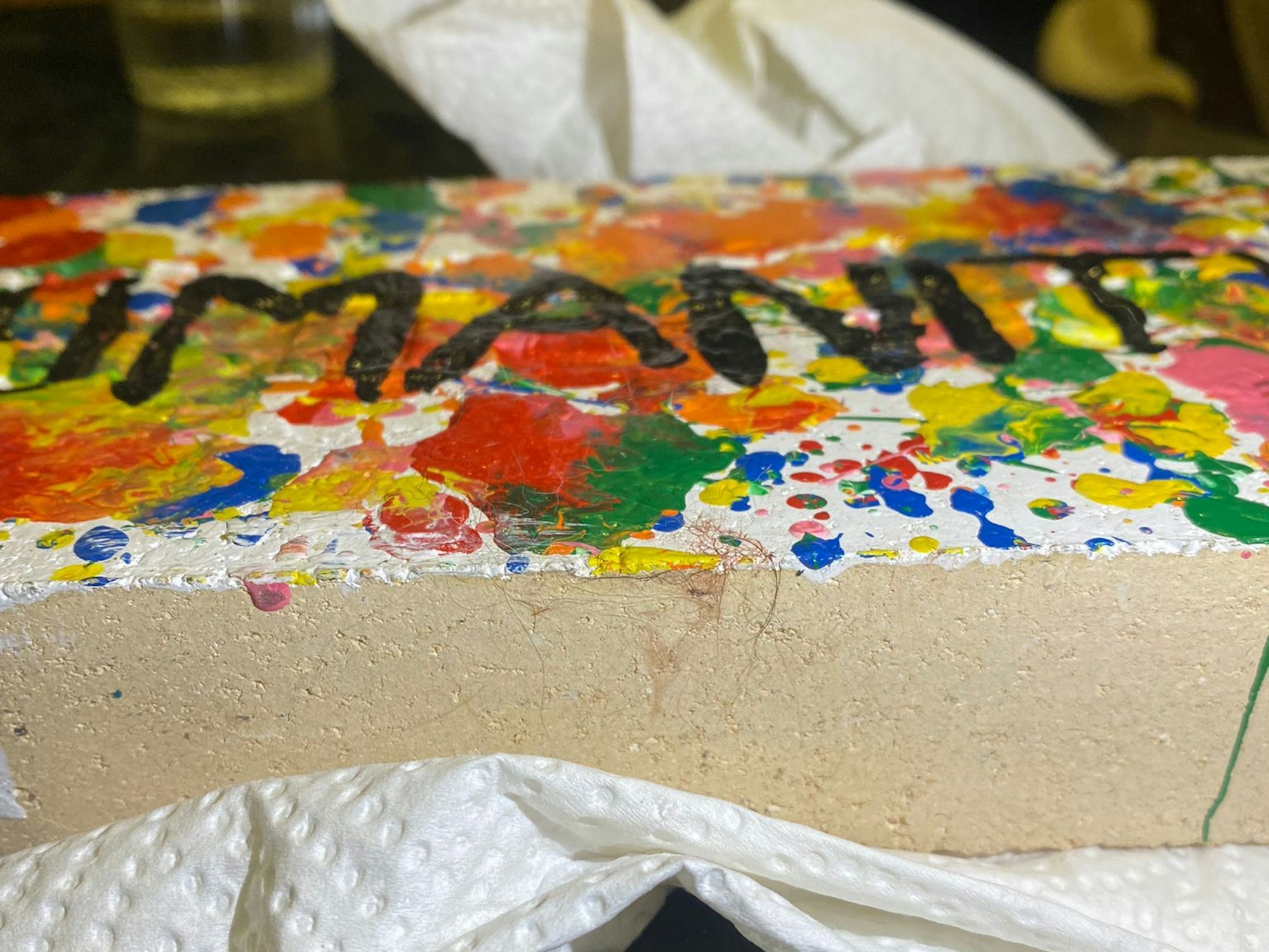 Ein angemalter Ziegelstein liegt auf einem Tisch.