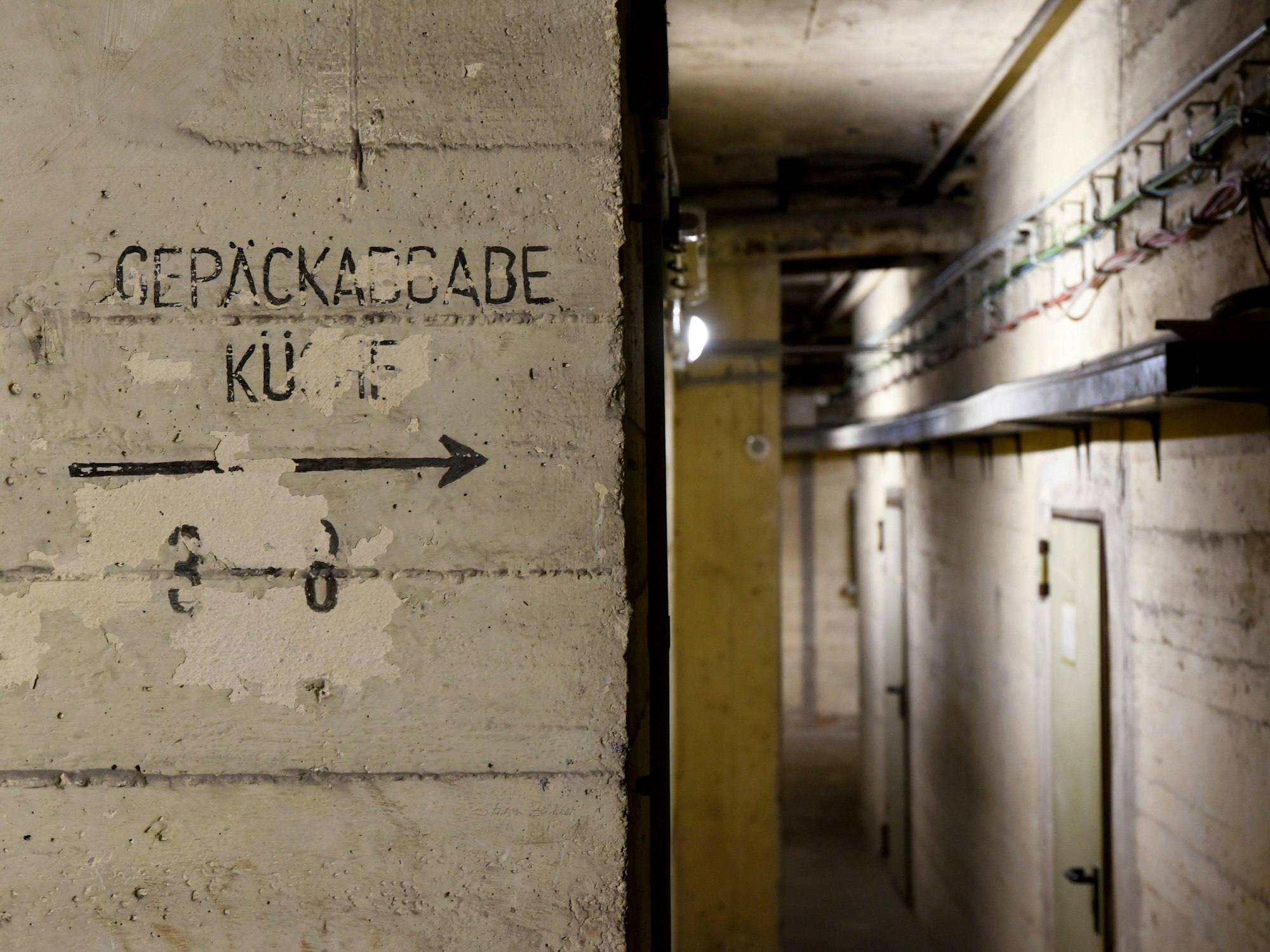 Blick in den Kölner Hochbunker am Kölner Hauptbahnhof – auf der Mauer steht „Gepäckabgabe“ und „Küche“.
