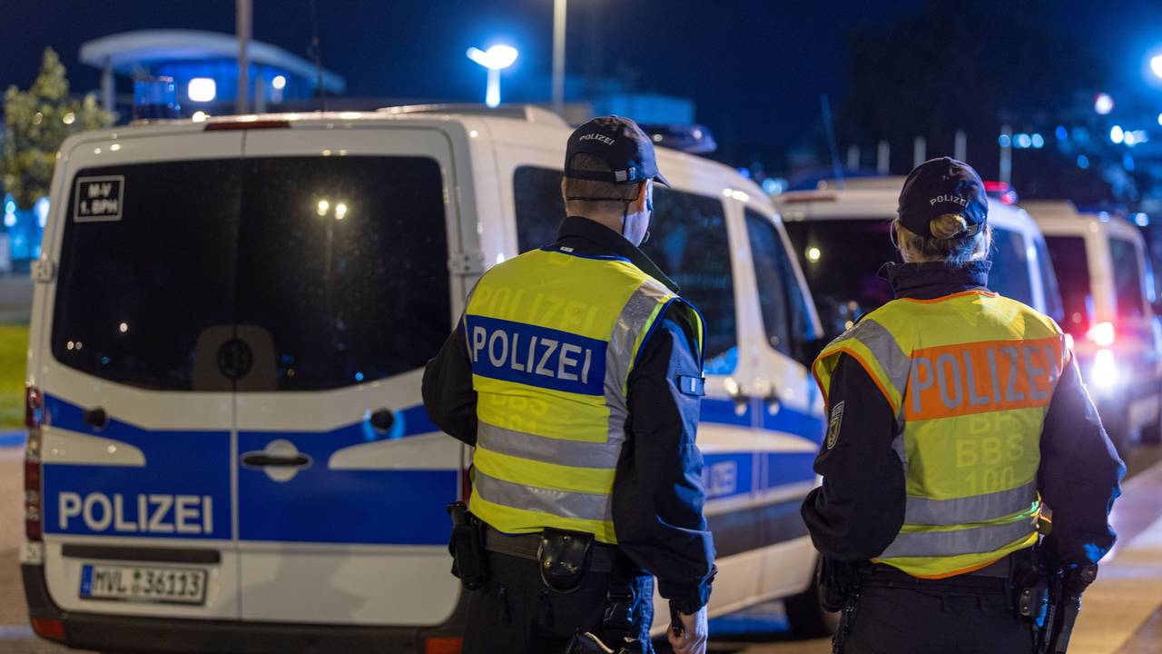 Mehrere Polizeifahrzeuge stehen an der Straße, davor eine Polizistin mit einem Kollege.