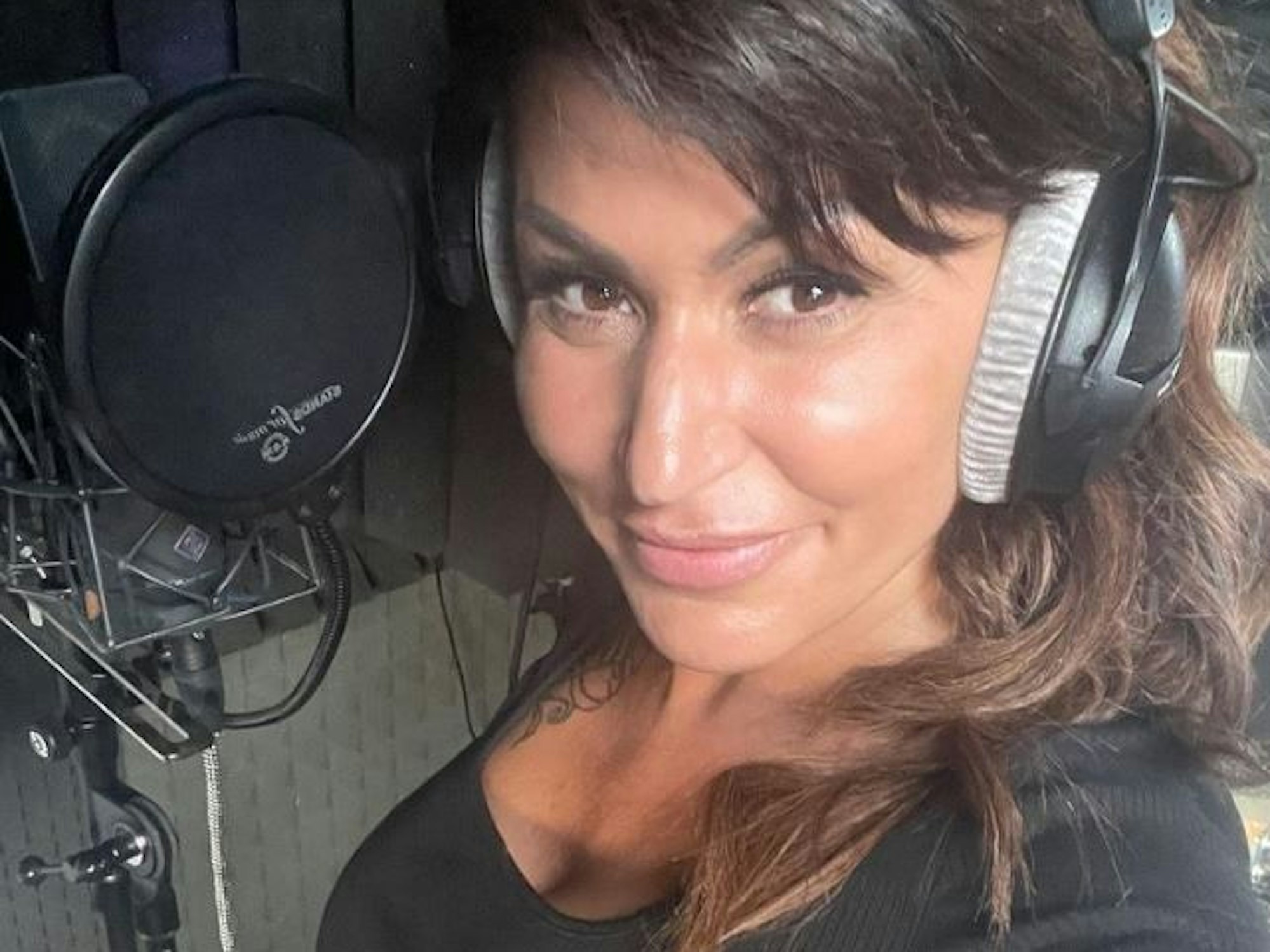 Jasmin Herren steht mit Kopfhören vor einem Mikrofon.