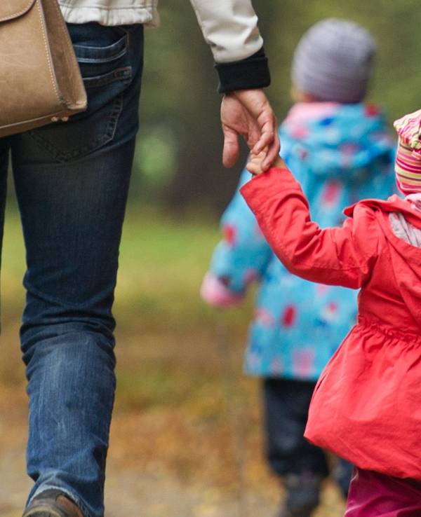 Eine Frau geht mit Kindern im Wald spazieren.