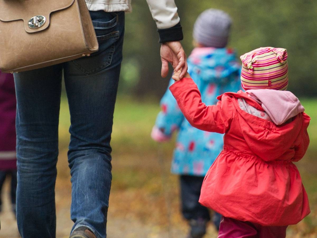 Eine Frau geht mit Kindern im Wald spazieren.