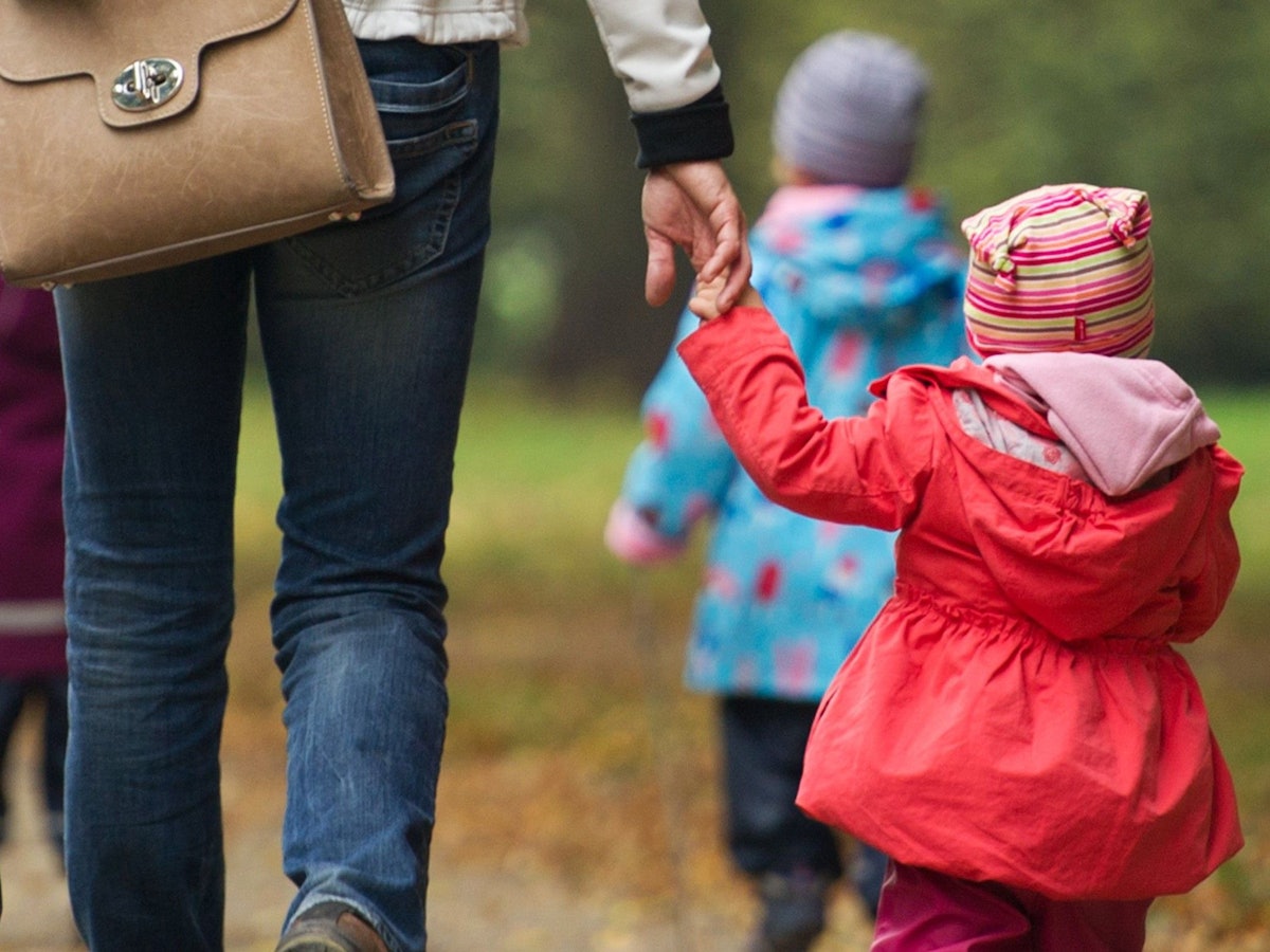 Eine Frau geht mit Kindern im Wald spazieren.