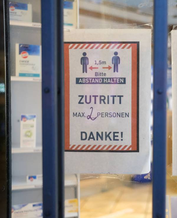 Hinweise mit Coronaschutzmaßnahmen an der Tür einer Apotheke.