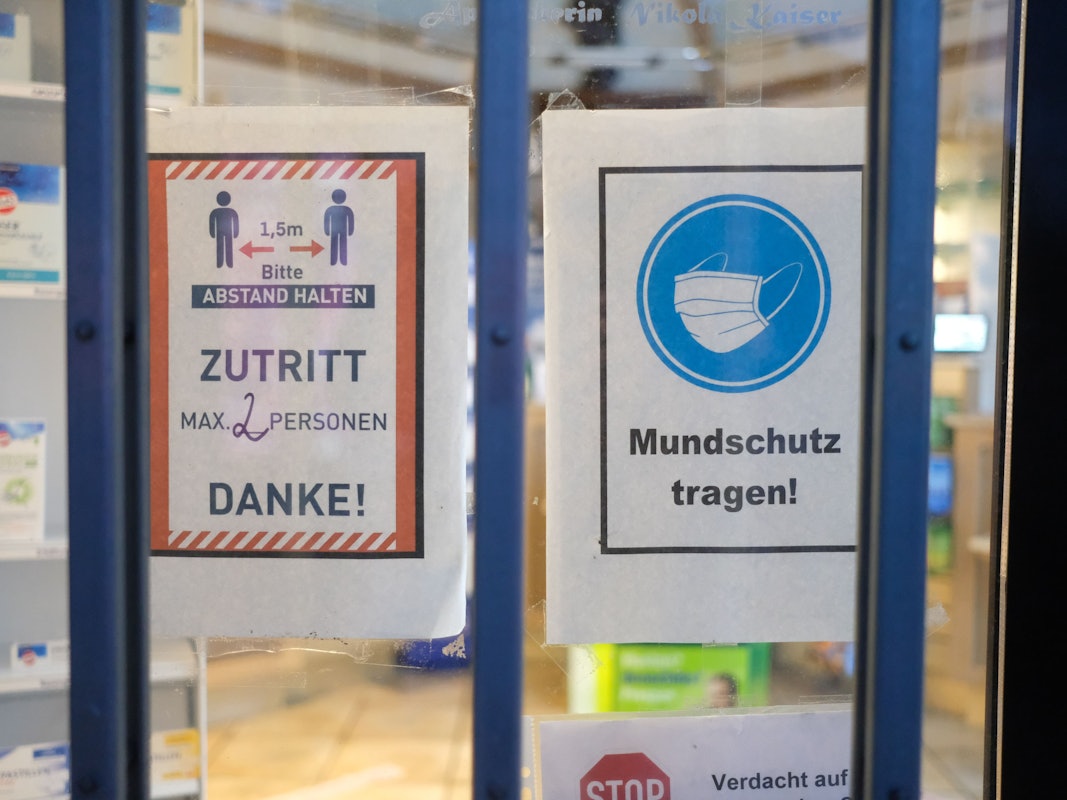 Hinweise mit Coronaschutzmaßnahmen an der Tür einer Apotheke.
