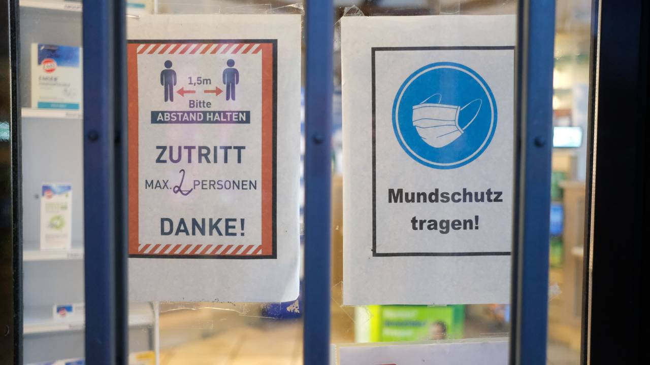 Hinweise mit Coronaschutzmaßnahmen an der Tür einer Apotheke.