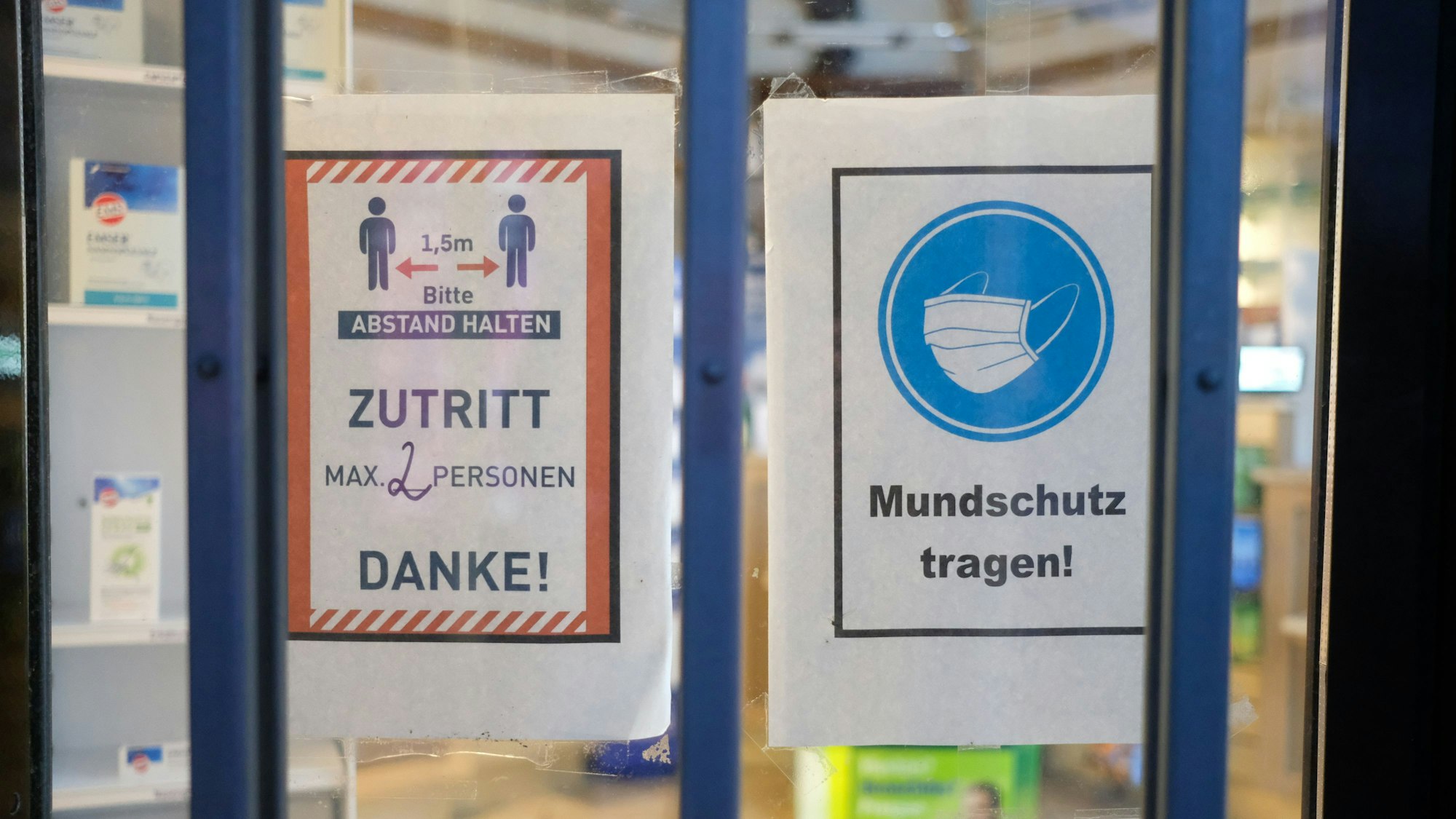 Hinweise mit Coronaschutzmaßnahmen an der Tür einer Apotheke.