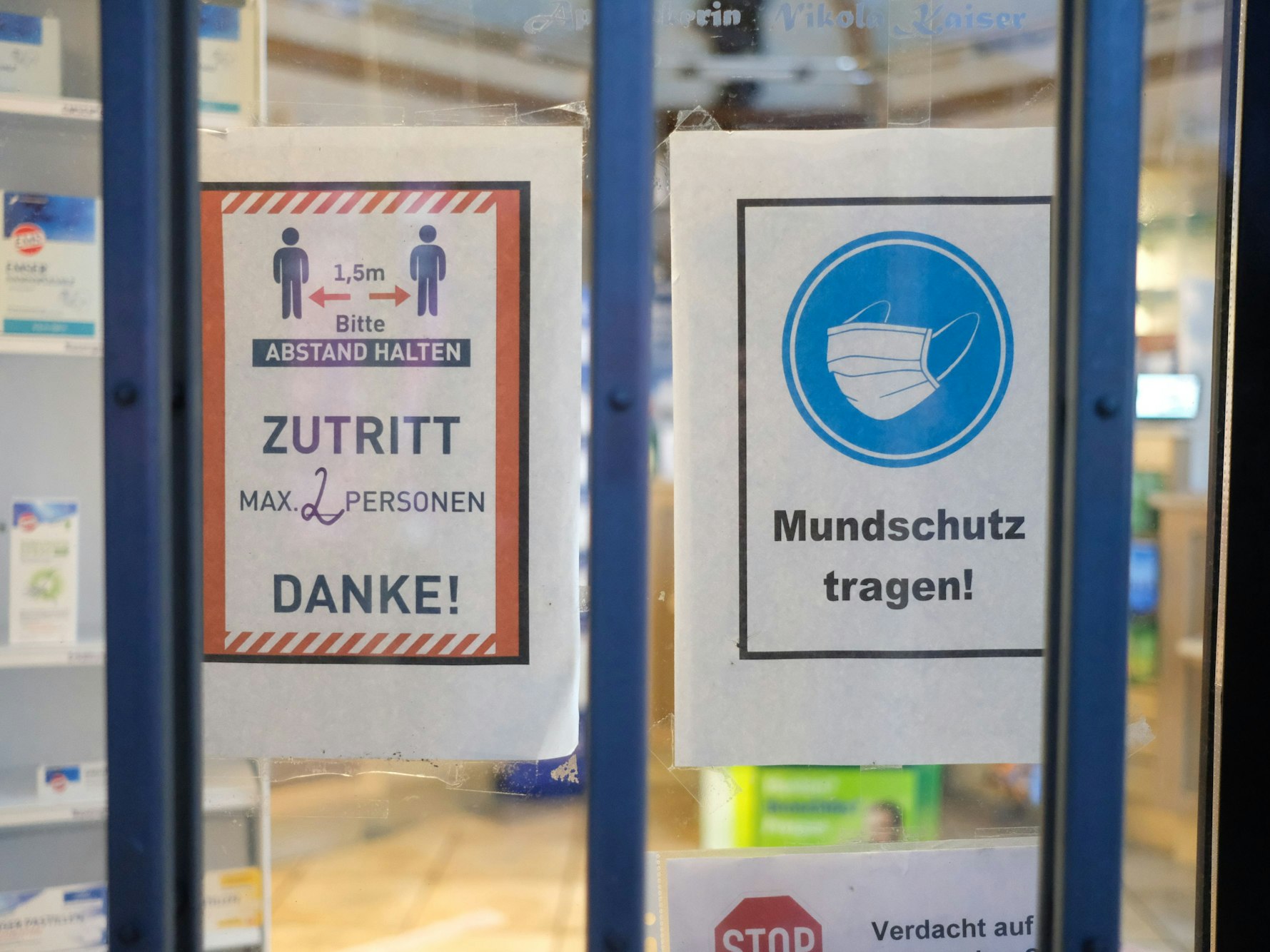 Hinweise mit Coronaschutzmaßnahmen an der Tür einer Apotheke.
