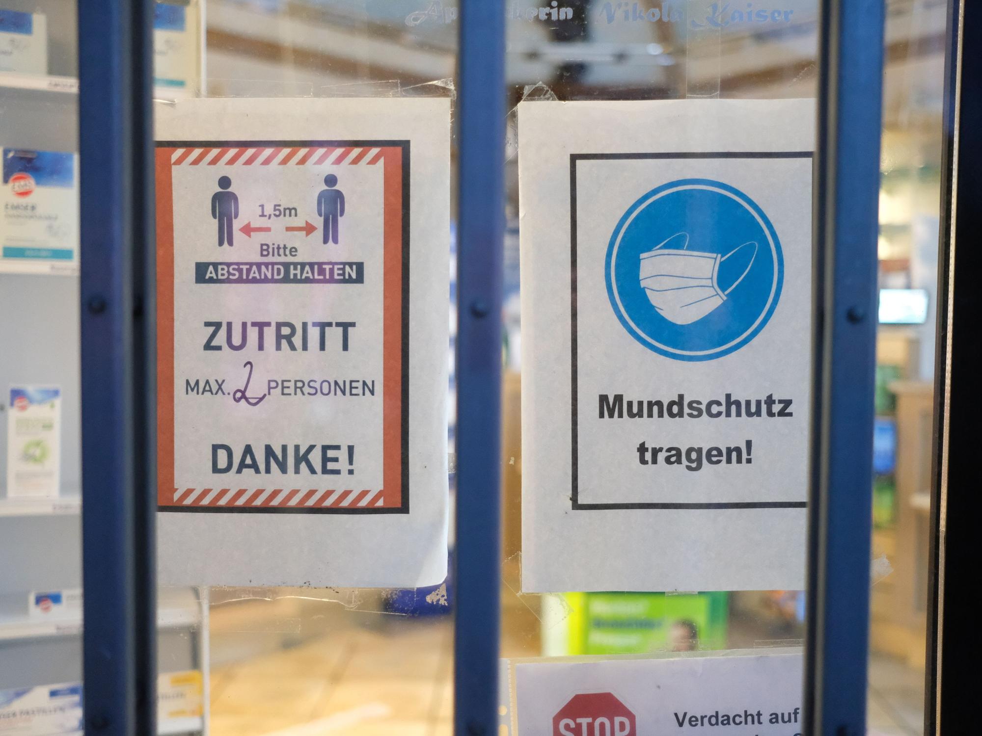 Hinweise mit Coronaschutzmaßnahmen an der Tür einer Apotheke.