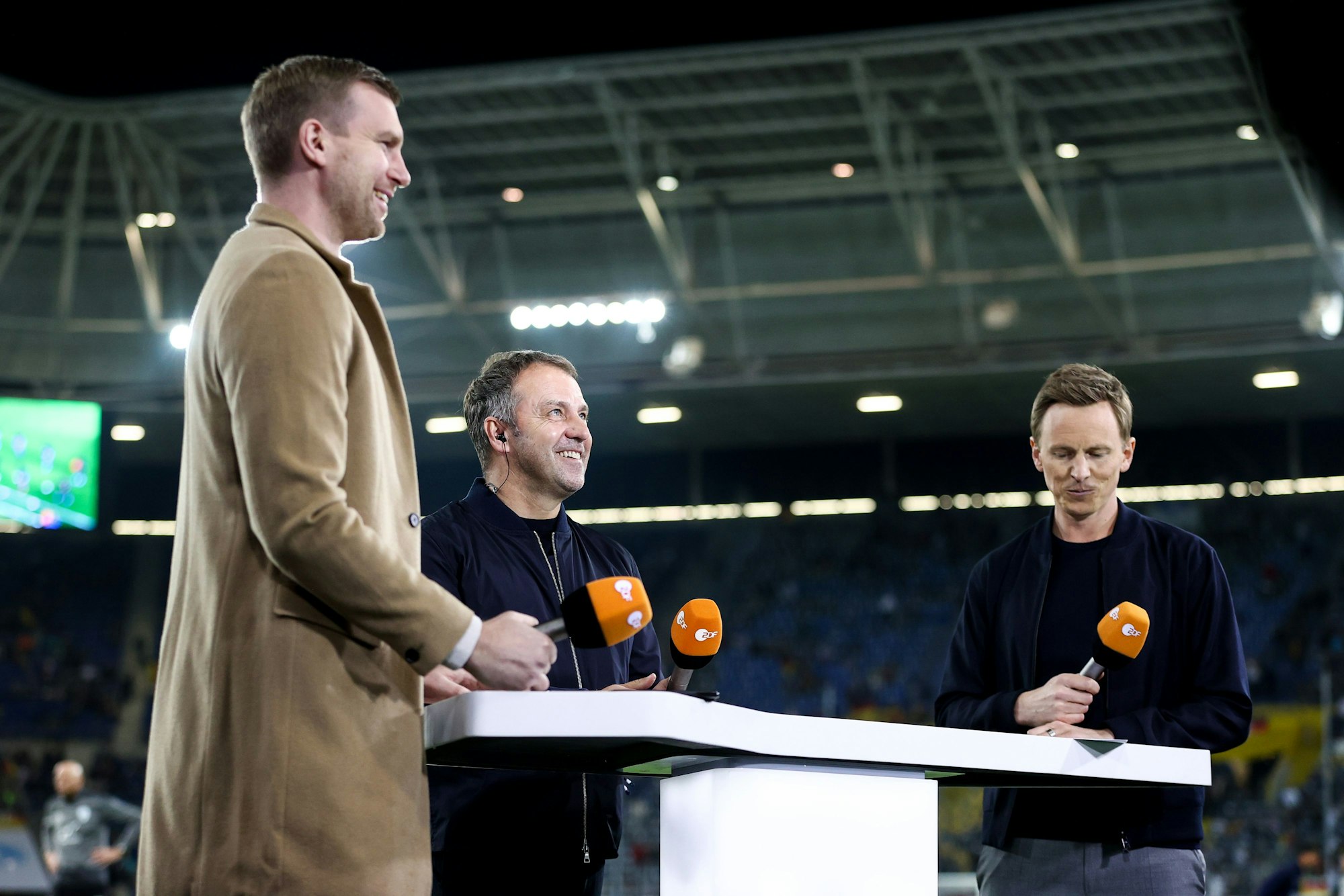 Deutschlands Trainer Hans-Dieter Flick (M.) im Interview mit dem ehemaligen Nationalspieler Per Mertesacker (l.) und TV-Moderator Jochen Breyer vom ZDF.