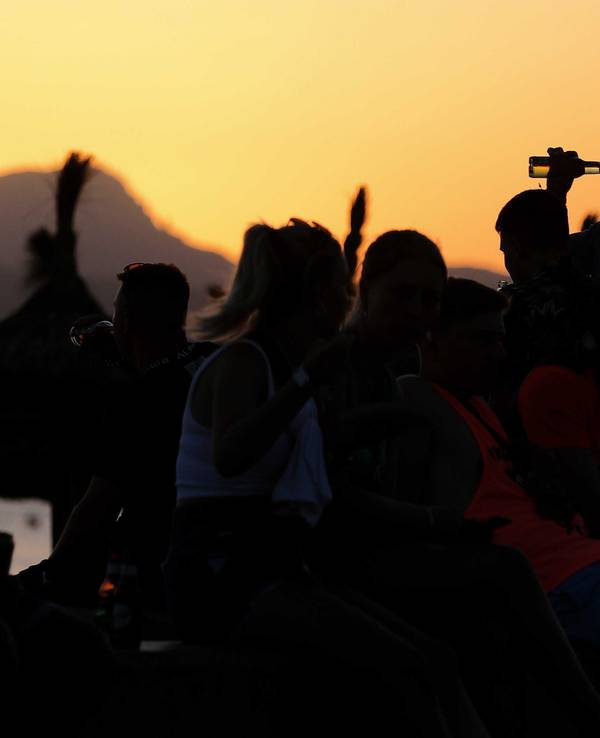 Das undatierte Symbolfoto zeigt mehrere Menschen, die vor einem Sonnenuntergang feiern.
