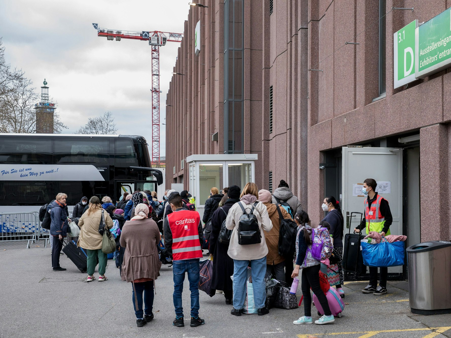 Geflüchtete Menschen stehen vor dem Eingang der Koelnmesse. Dort werden die Menschen zeitweise untergebracht.