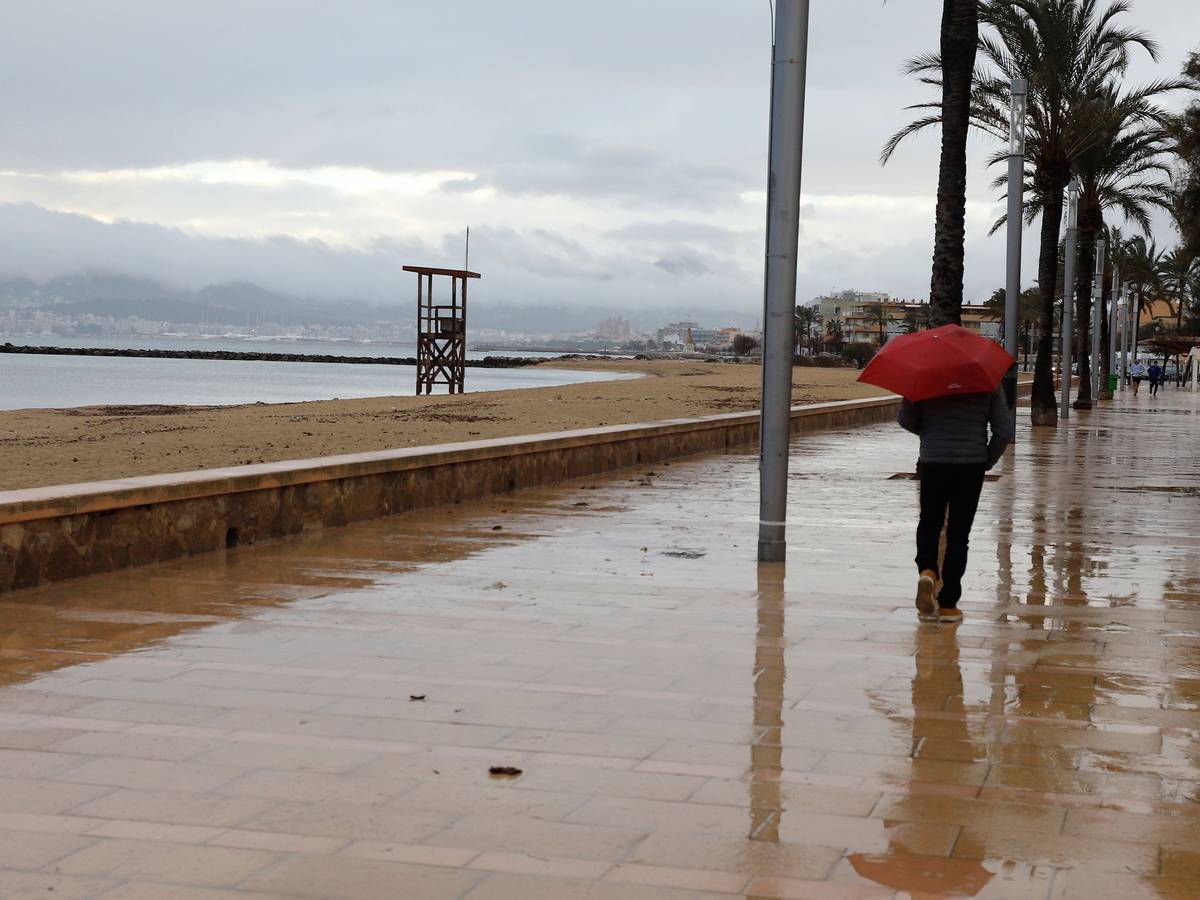 Ein Mann spaziert mit einem Regenschirm am Strand von Palma entlang.