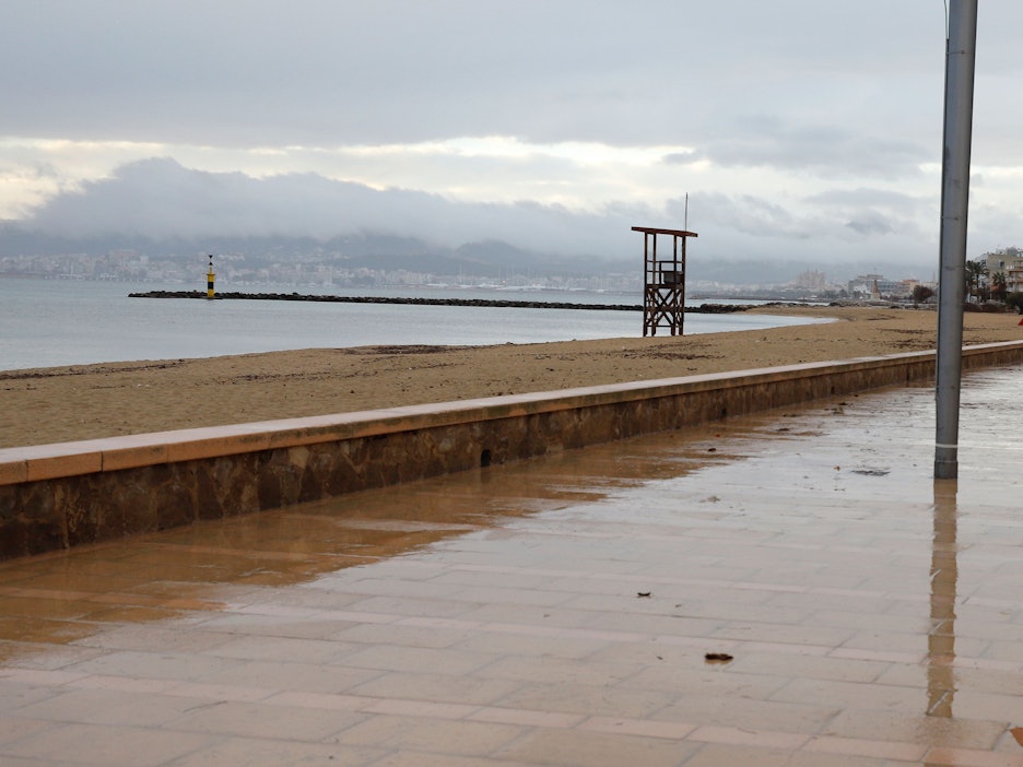 Ein Mann spaziert mit einem Regenschirm am Strand von Palma entlang.