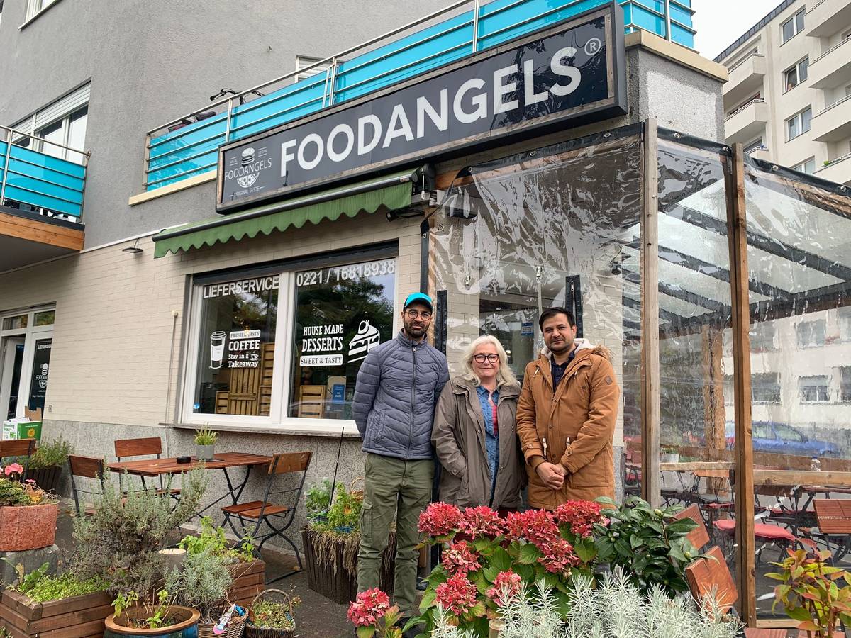 Inhaber Mazlom Sediqi, Unterstützerin Susanne Zeltinger und Fazal Rabi Rahimzai stehen vor dem Foodangels-Bistro auf der Kölner Etzelstraße.