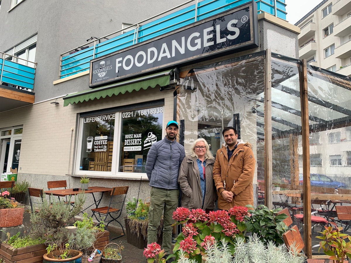 Inhaber Mazlom Sediqi, Unterstützerin Susanne Zeltinger und Fazal Rabi Rahimzai stehen vor dem Foodangels-Bistro auf der Kölner Etzelstraße.