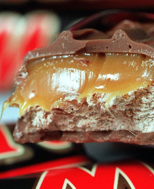 Ein Schokoriegel "Mars" liegt angebissen auf noch verpackten Riegeln.