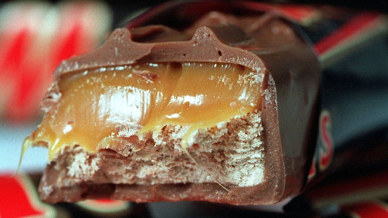 Ein Schokoriegel "Mars" liegt angebissen auf noch verpackten Riegeln.