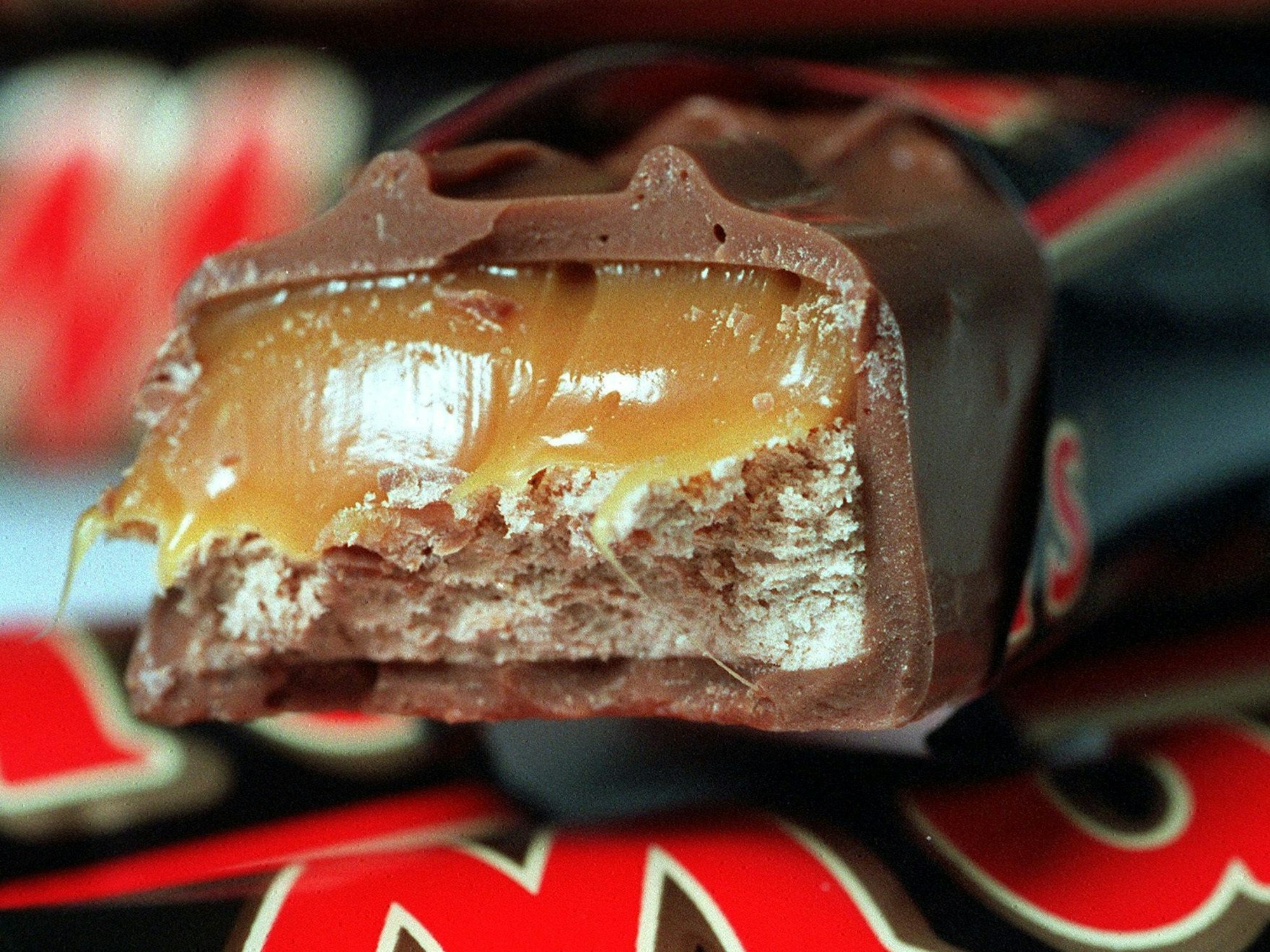 Ein Schokoriegel "Mars" liegt angebissen auf noch verpackten Riegeln.