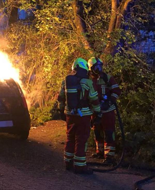 Die Feuerwehr löscht ein brennendes Auto.