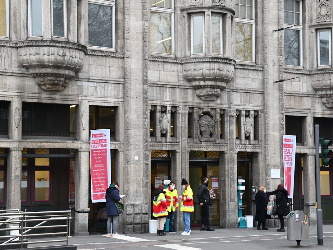 Mehrere Personen stehen vor dem Kölner Gesundheitsamt am Neumarkt.