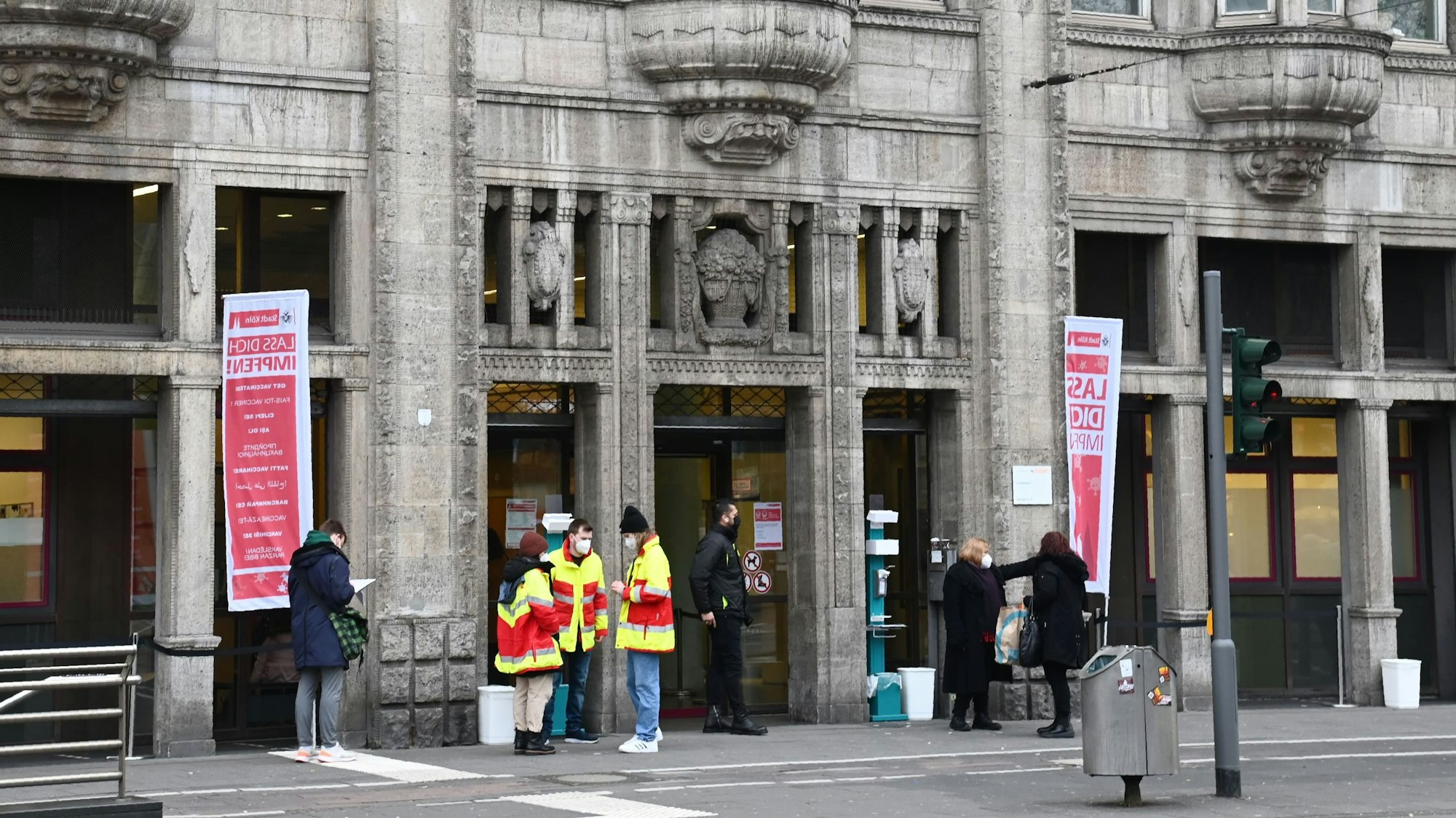 Mehrere Personen stehen vor dem Kölner Gesundheitsamt am Neumarkt.
