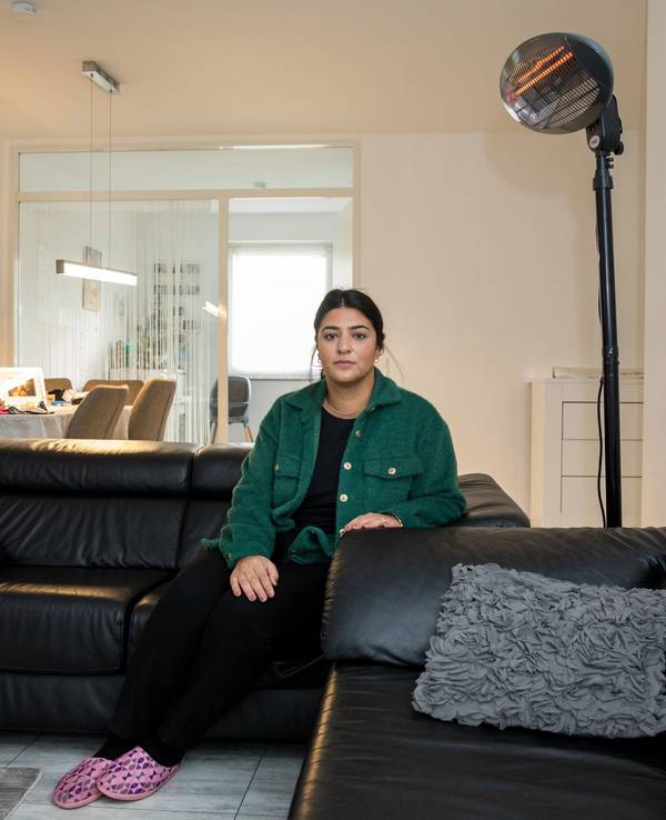 Eine Frau sitzt auf ihrem Sofa vor einem Heizstrahler.