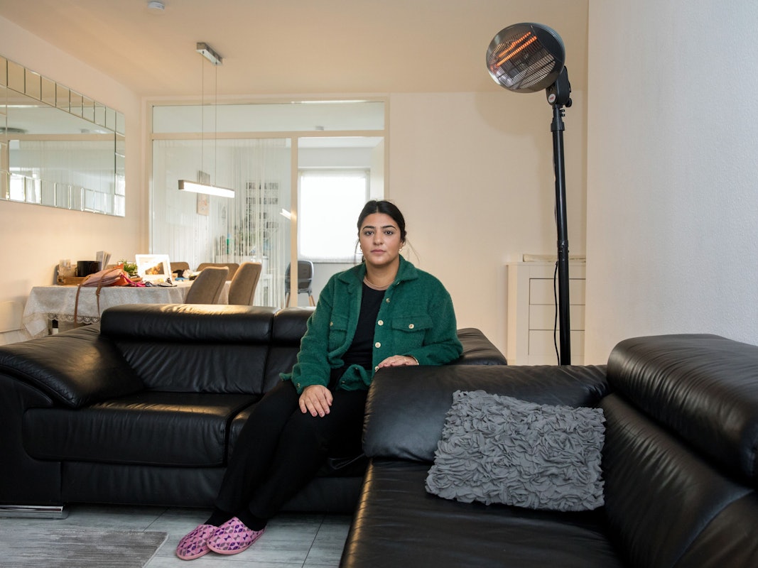 Eine Frau sitzt auf ihrem Sofa vor einem Heizstrahler.