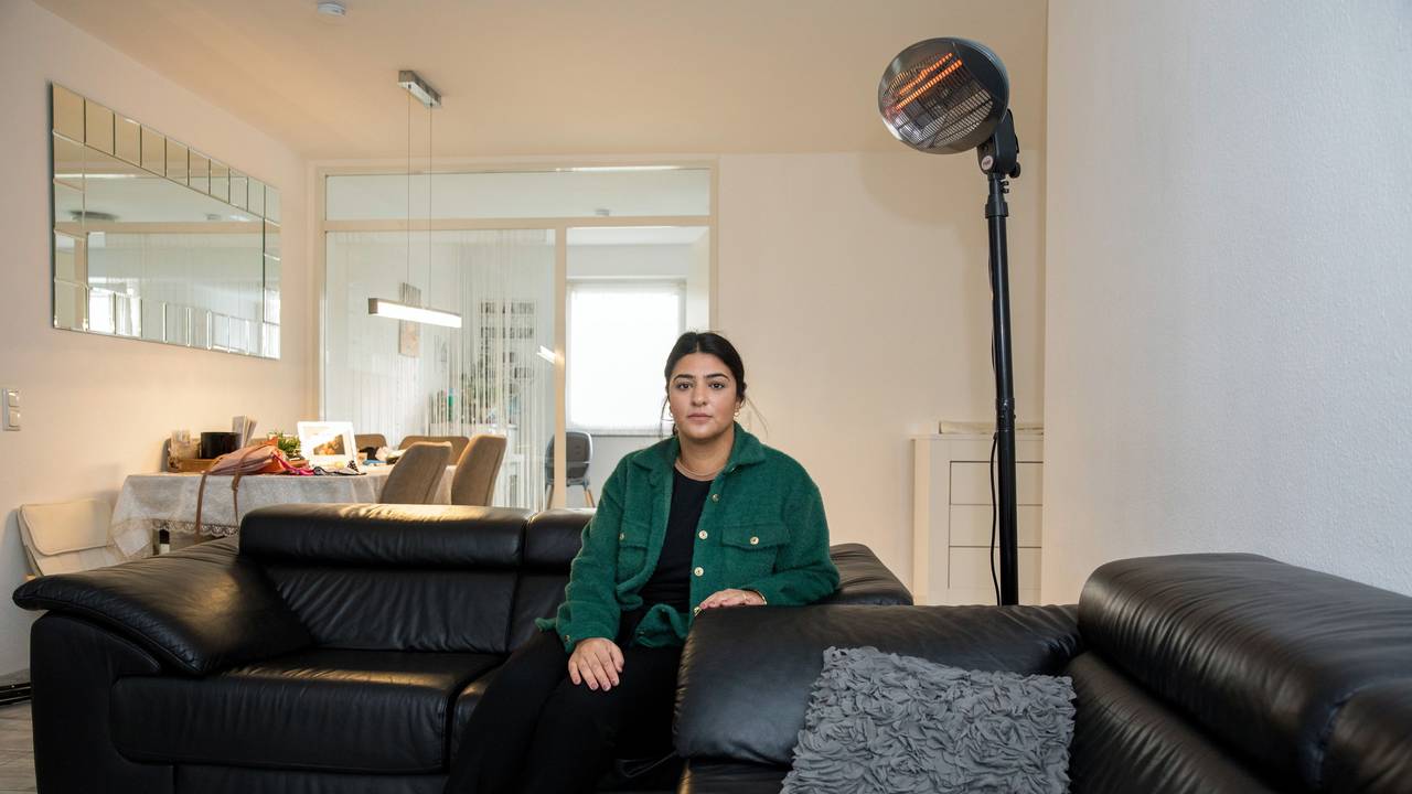 Eine Frau sitzt auf ihrem Sofa vor einem Heizstrahler.