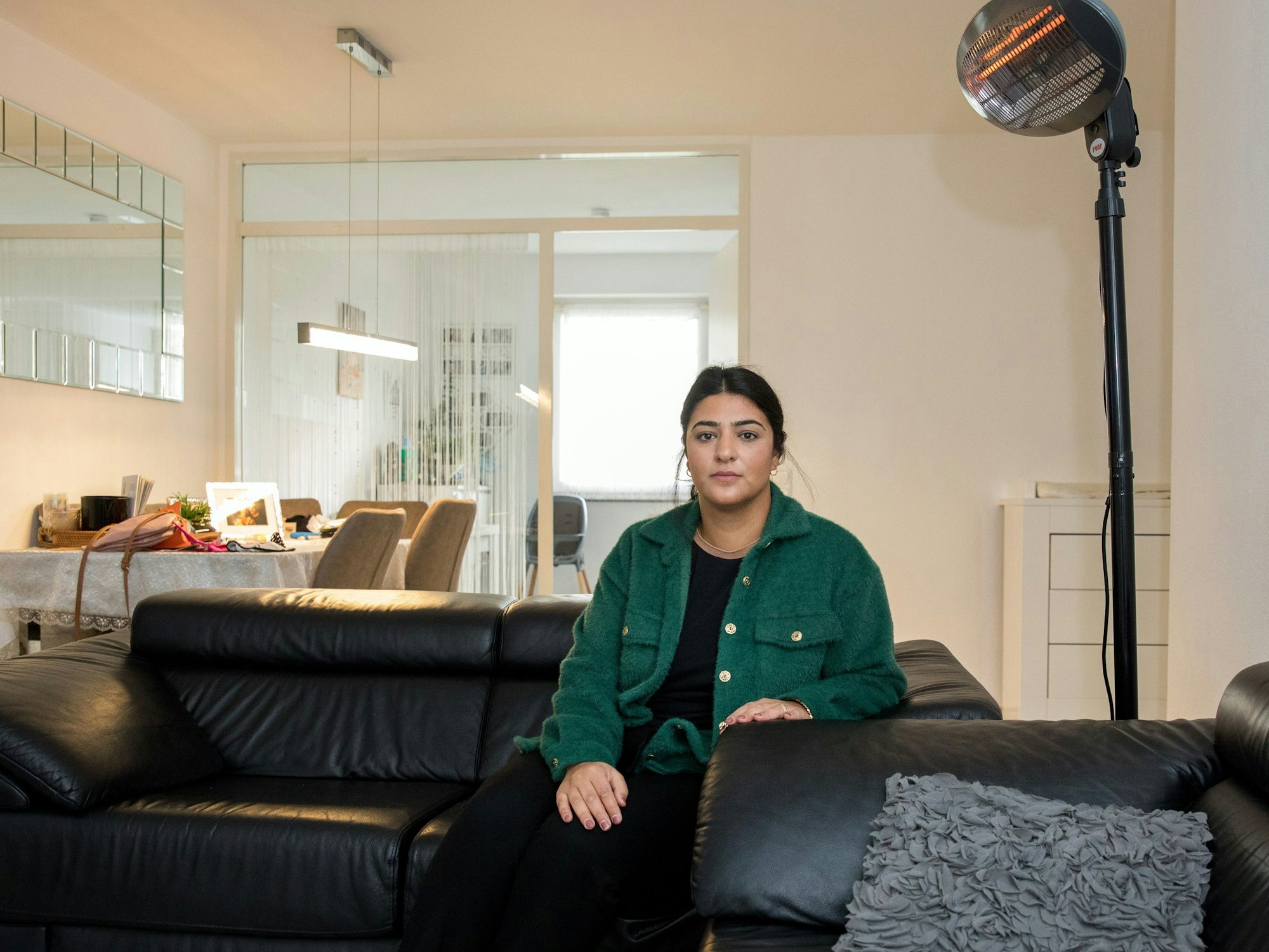 Eine Frau sitzt auf ihrem Sofa vor einem Heizstrahler.