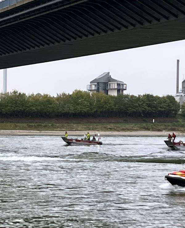 Einsatzkräfte fahren den Rhein mit Booten ab.