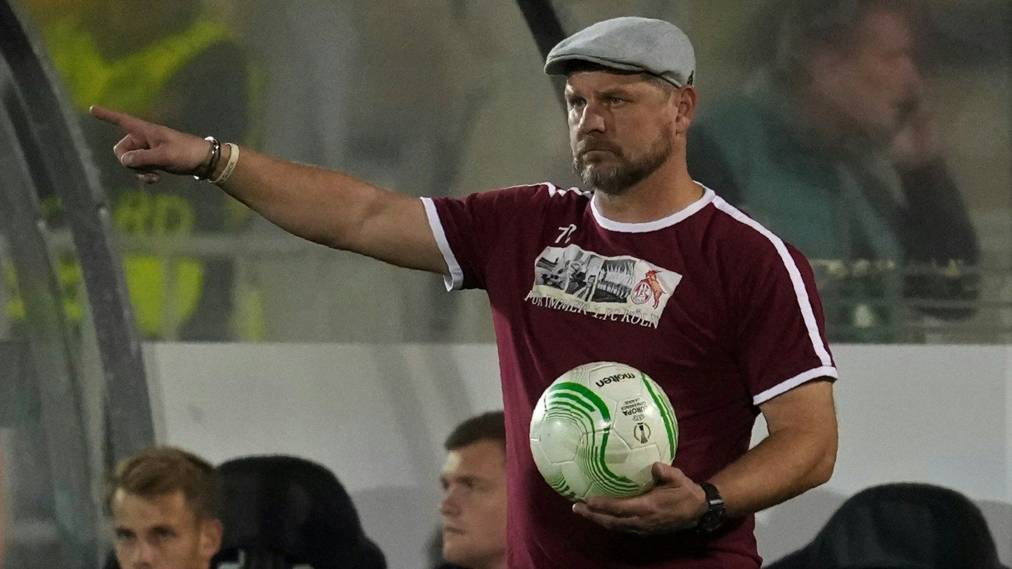 Steffen Baumgart hält bei einem Spiel des 1. FC Köln in der Conference League den Ball in der Hand und gibt mit ausgestrecktem Zeigefinger Anweisungen