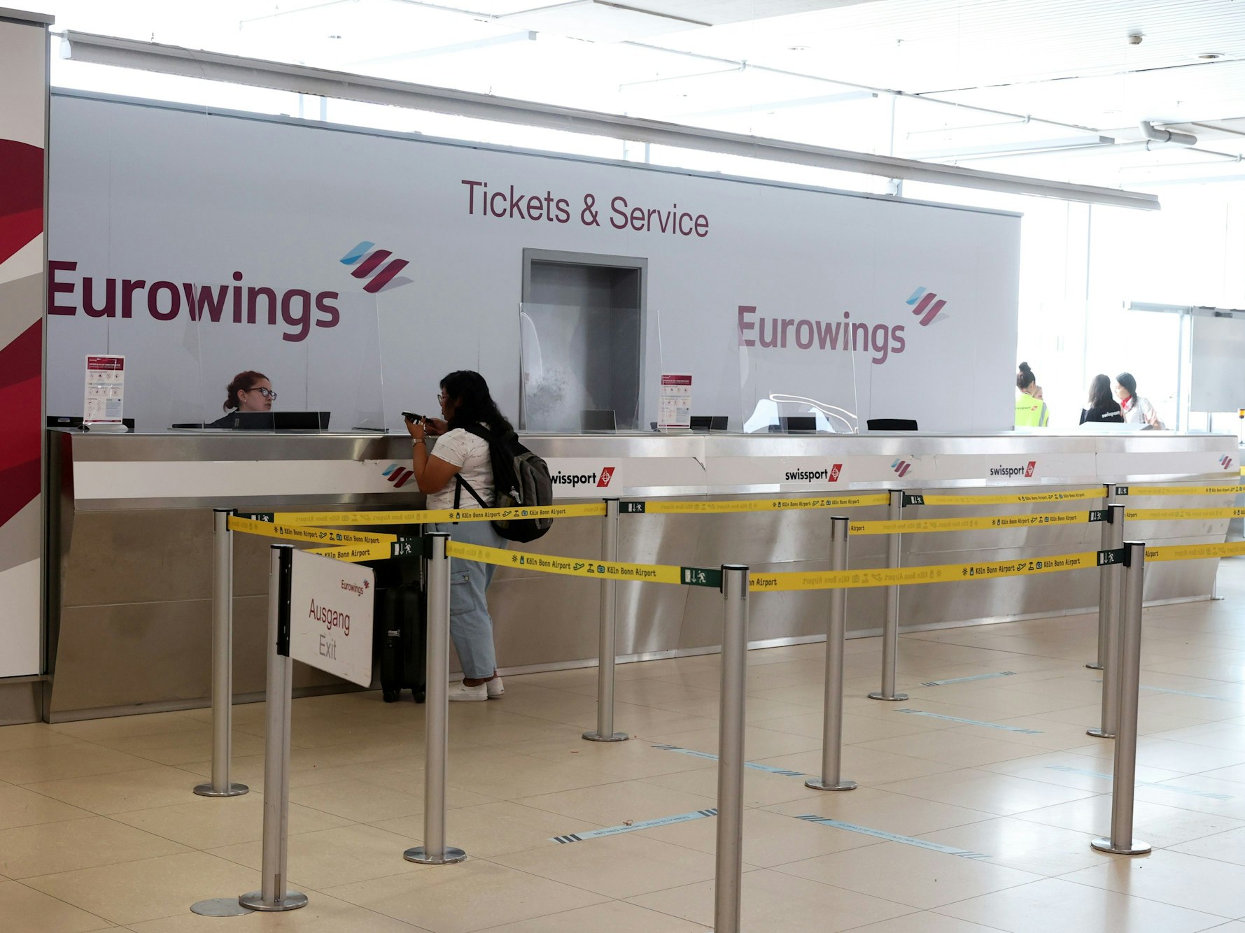 Eine Frau steht am Flughafen Köln/Bonn am Schalter von Eurowings.