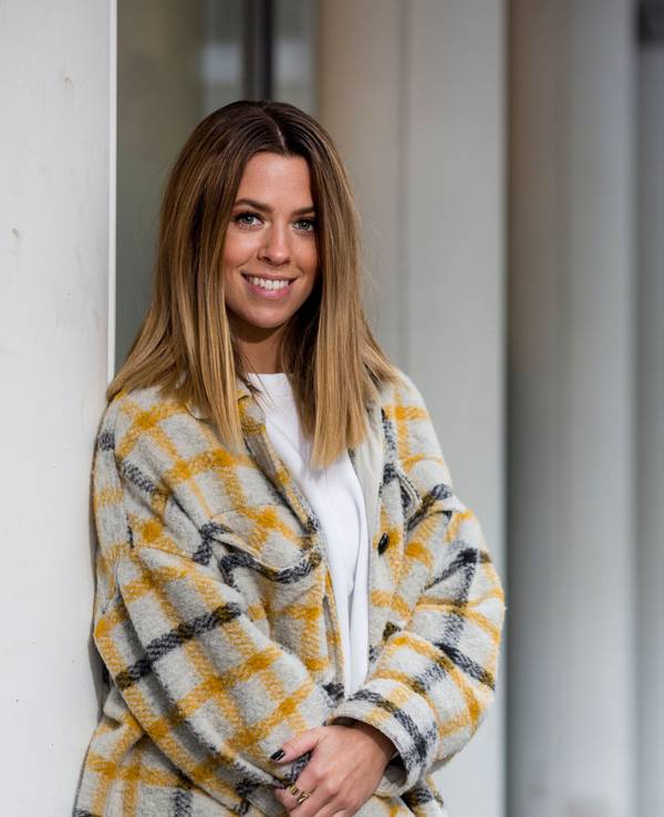 Vanessa Mai lacht fröhlich in einer bunten Strickjacke in die Kamera.
