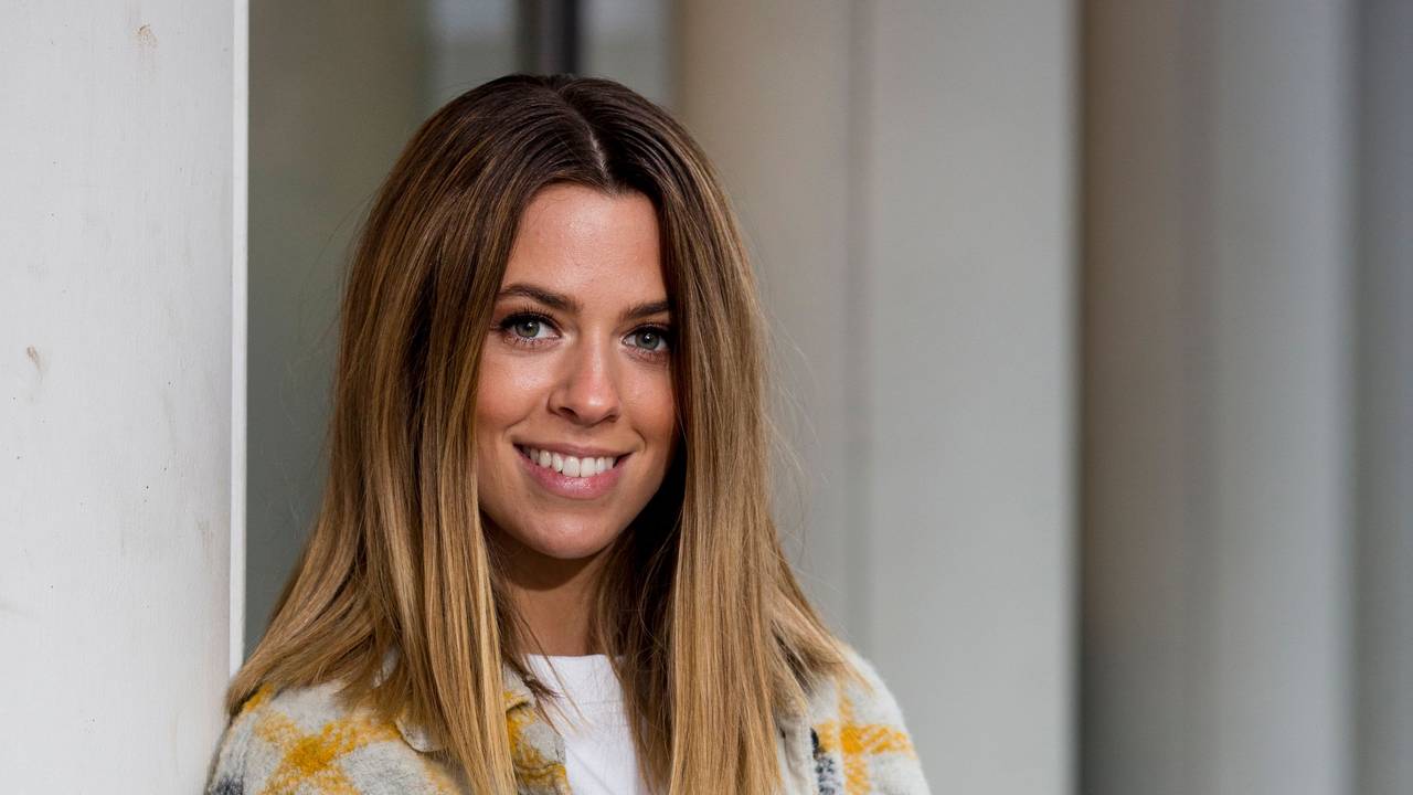 Vanessa Mai lacht fröhlich in einer bunten Strickjacke in die Kamera.