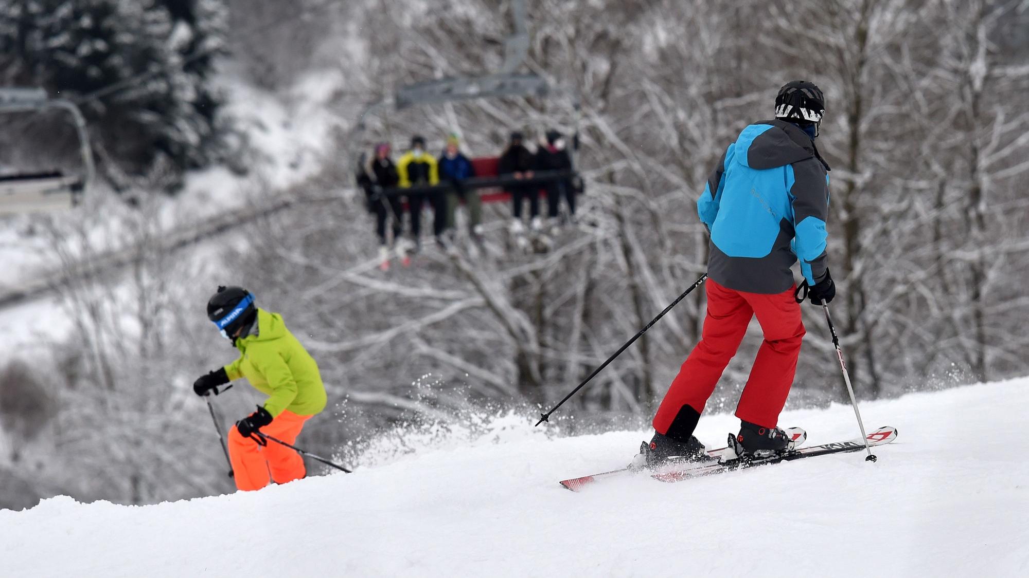 Das Symbolfoto zeigt zwei Personen mit Ski-Ausrüstung, die einen schneebedeckten Abhang hinunterfahren.