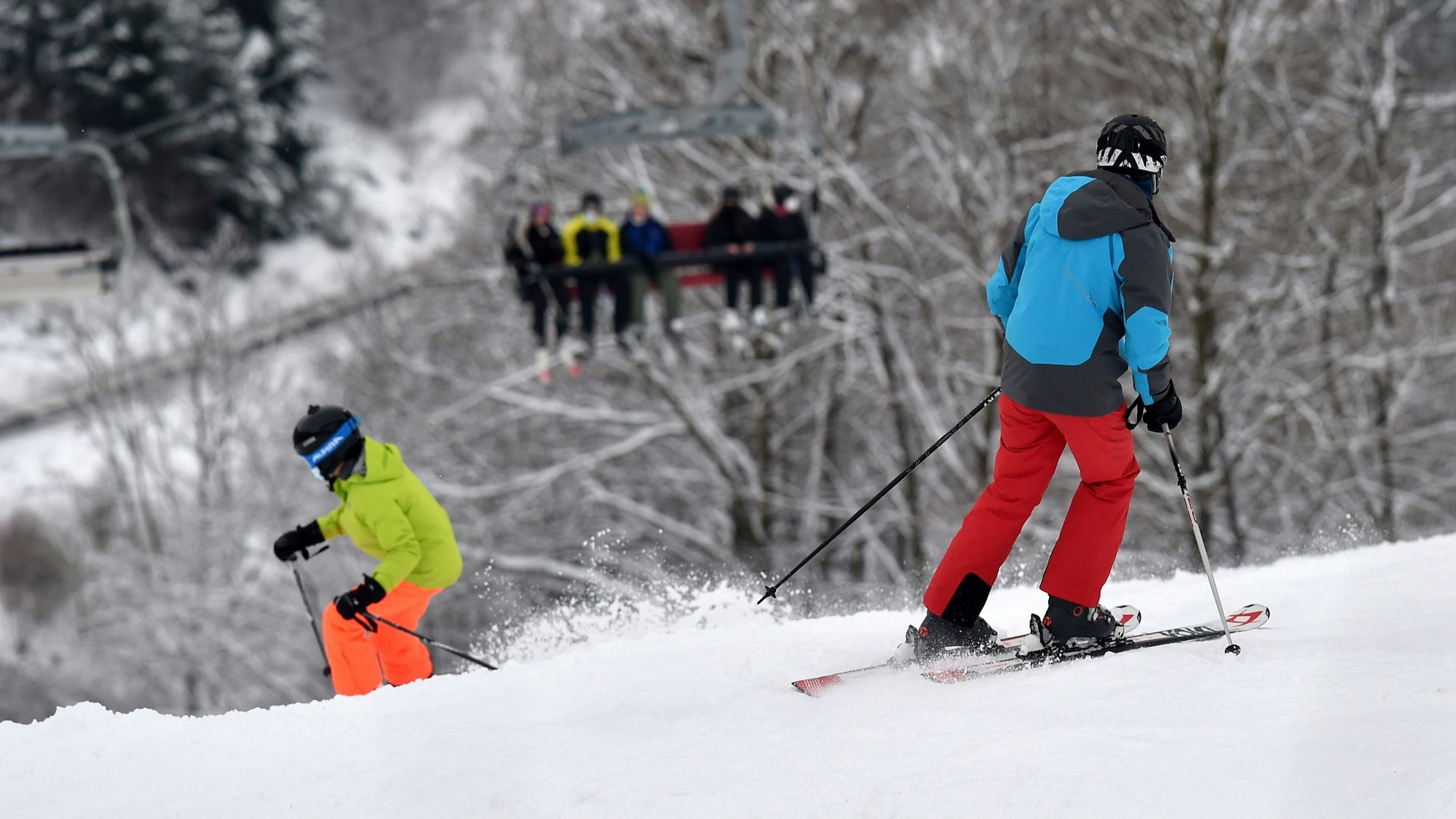 Das Symbolfoto zeigt zwei Personen mit Ski-Ausrüstung, die einen schneebedeckten Abhang hinunterfahren.